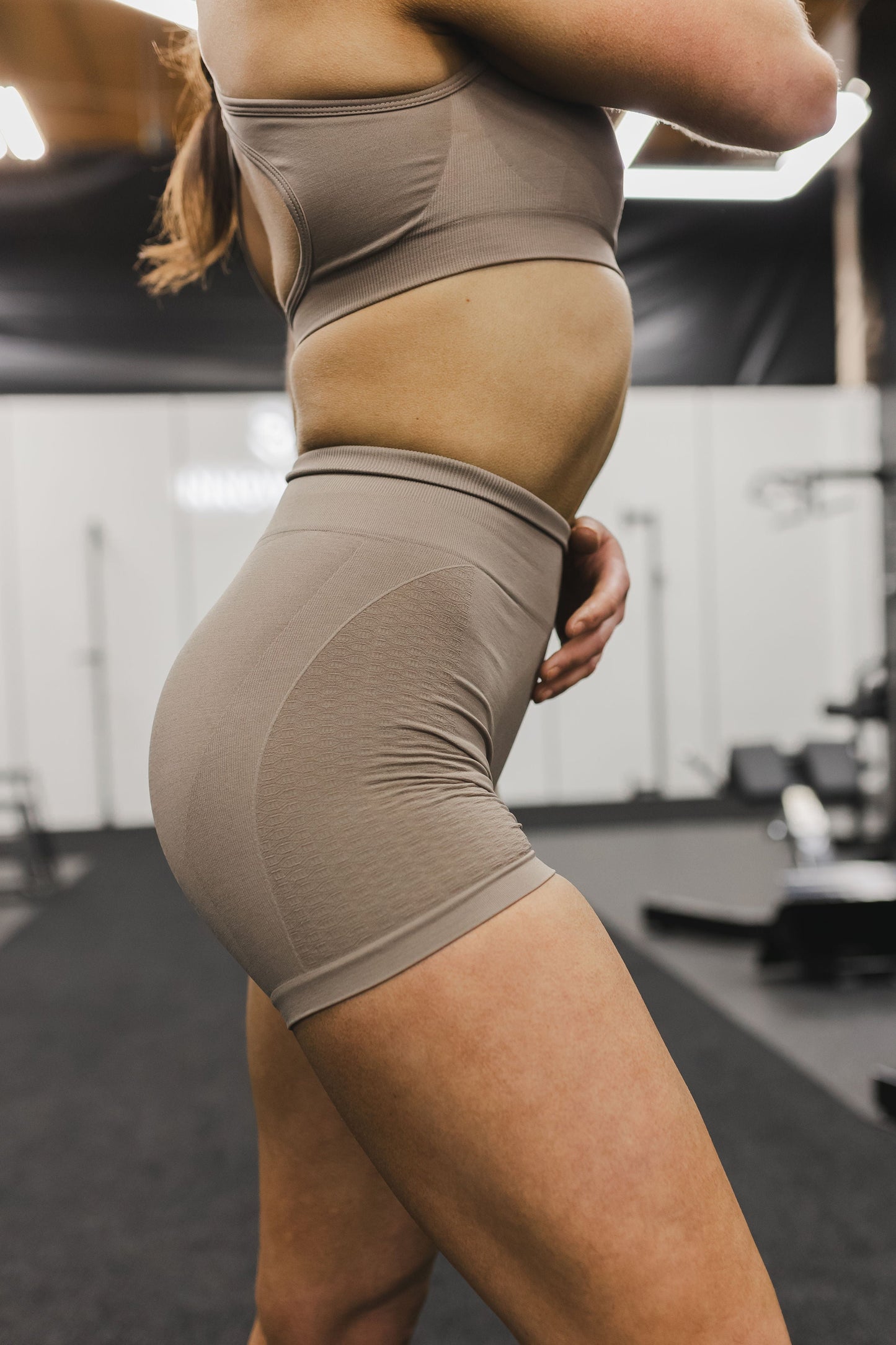 side view of a woman wearing mini scrunch shorts in desert storm for yoga and summer activewear
