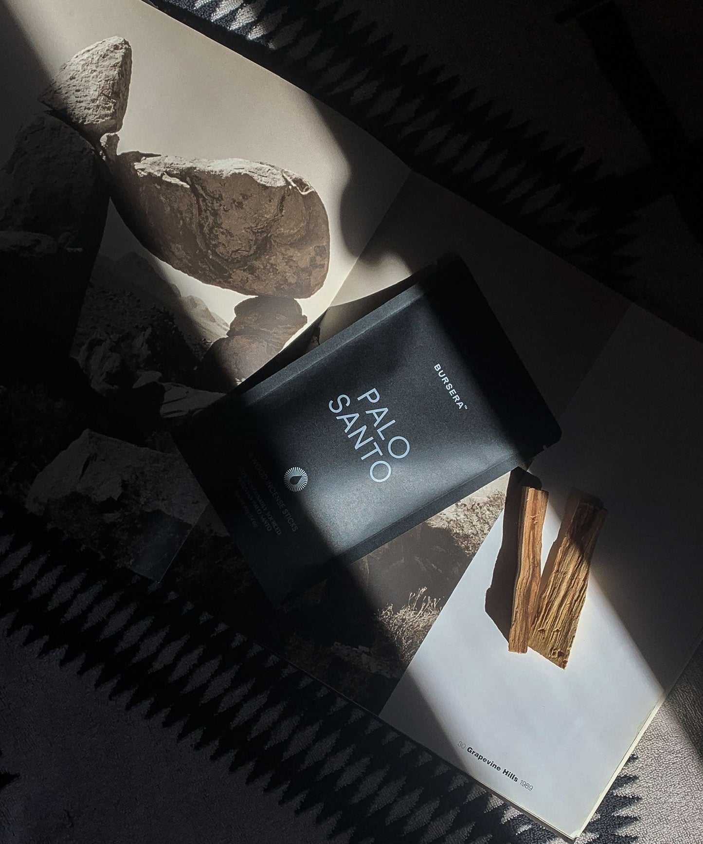 Black palo santo incense sticks aromatherapy on a magazine with rocks and sticks