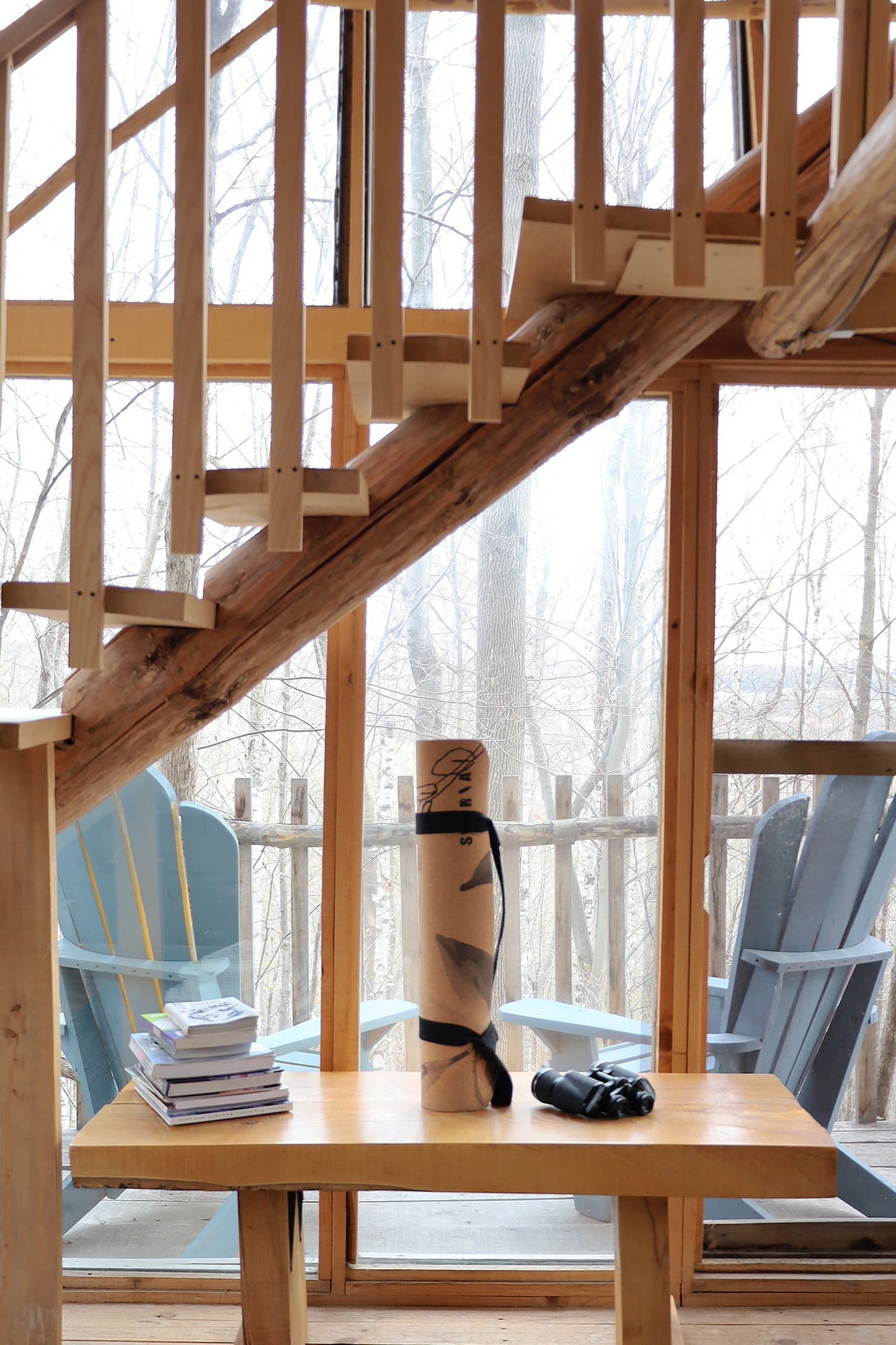 Wooden staircase leading to a deck with Adirondack chairs and a yoga mat rolled up