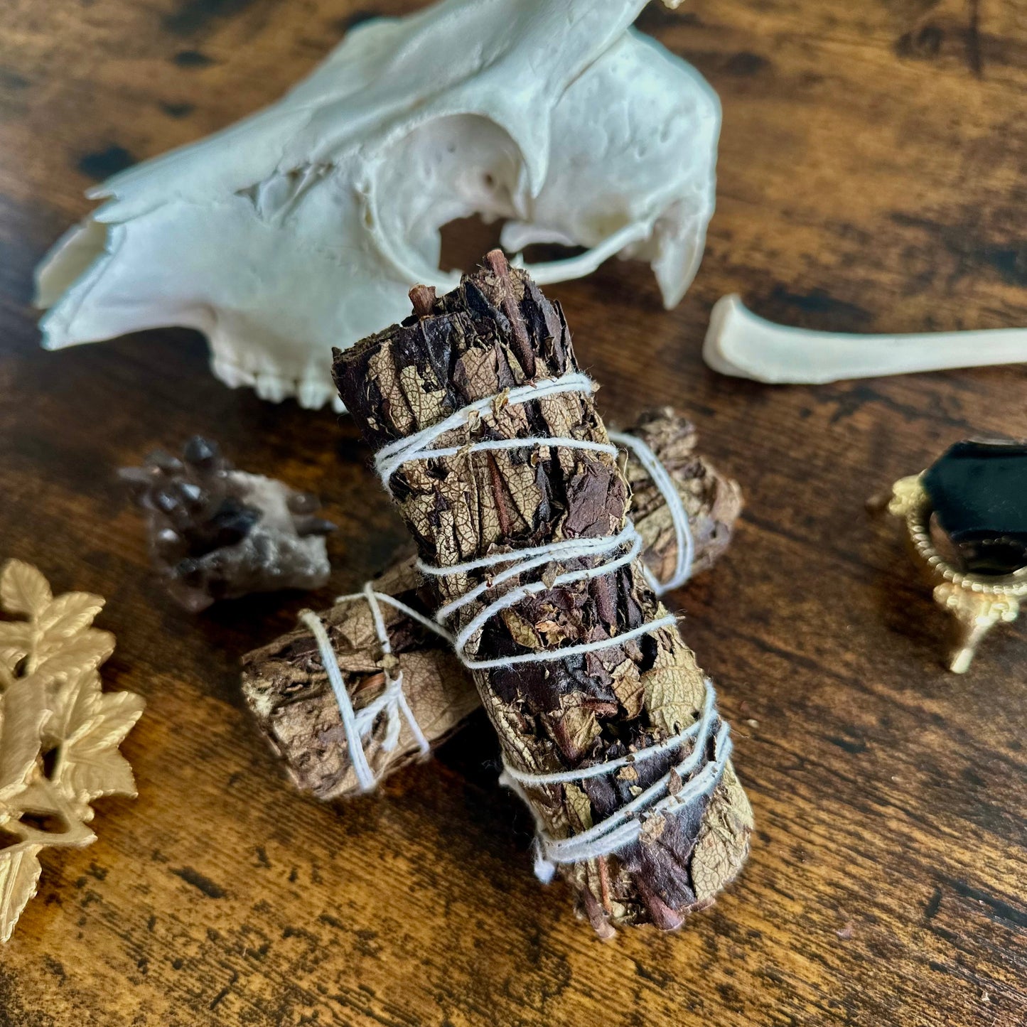 Bundled sage on a wooden surface with a skull and decorative items.