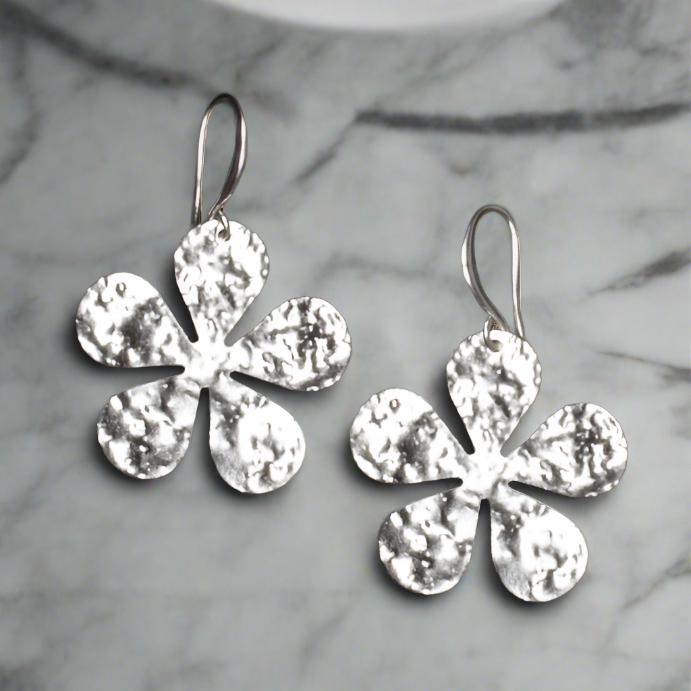 Gold plate hammered flower drop earrings artisan boho jewelry up close on dark background