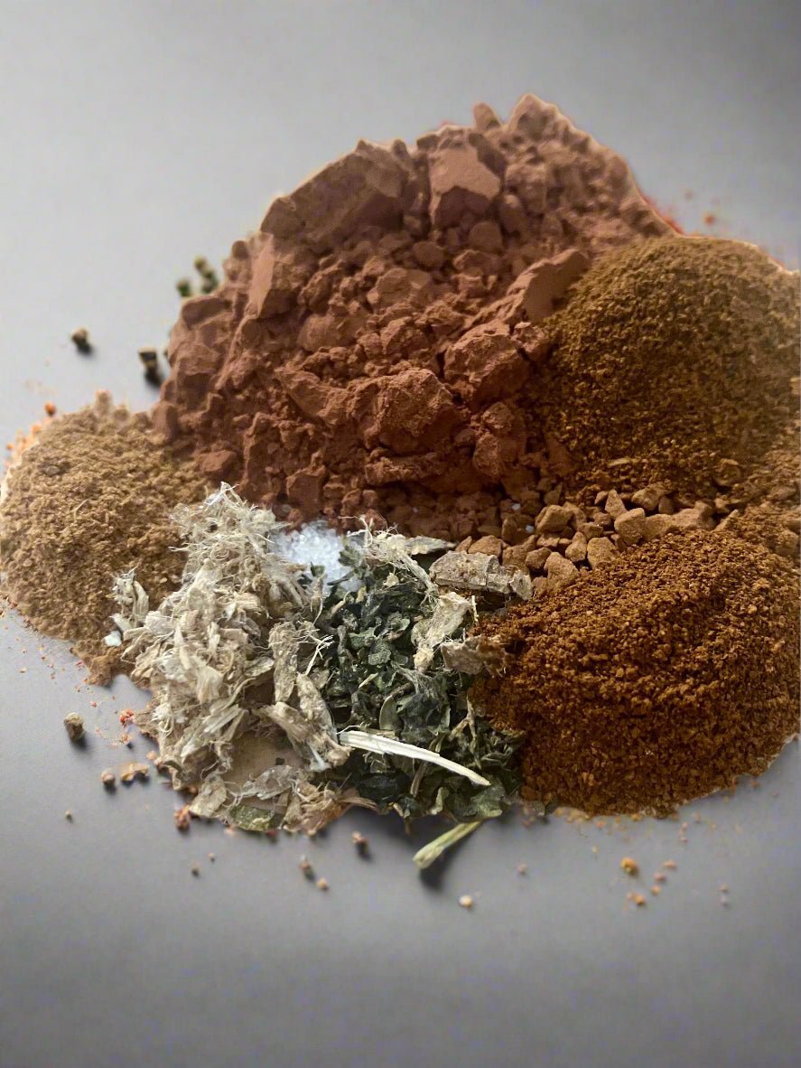 Spices including ground brown, red, and green on a gray background