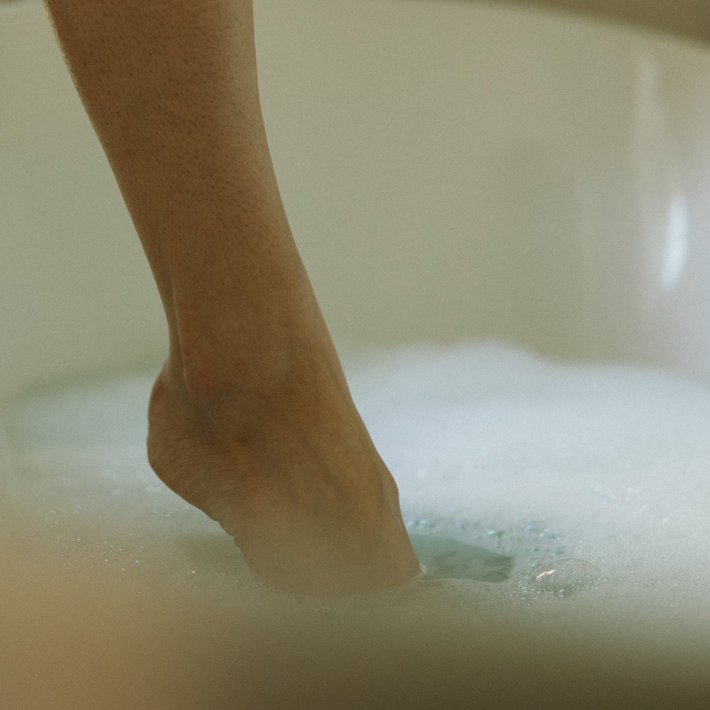 Foot stepping into a bubble bath