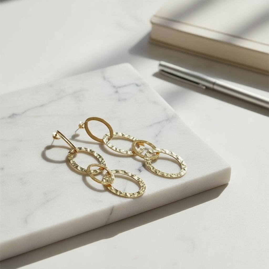 Gold stainless steel linked oval drop earrings made in bali minimalist jewelry on a tray