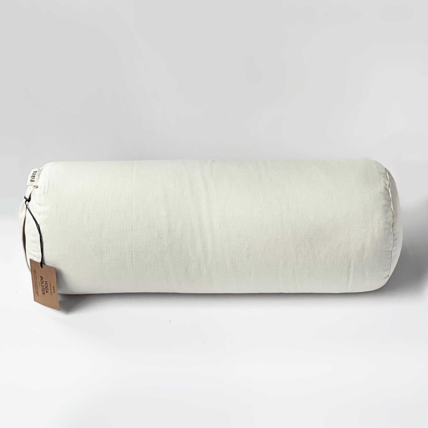 White cylindrical pillow with a brown tag on a light gray background