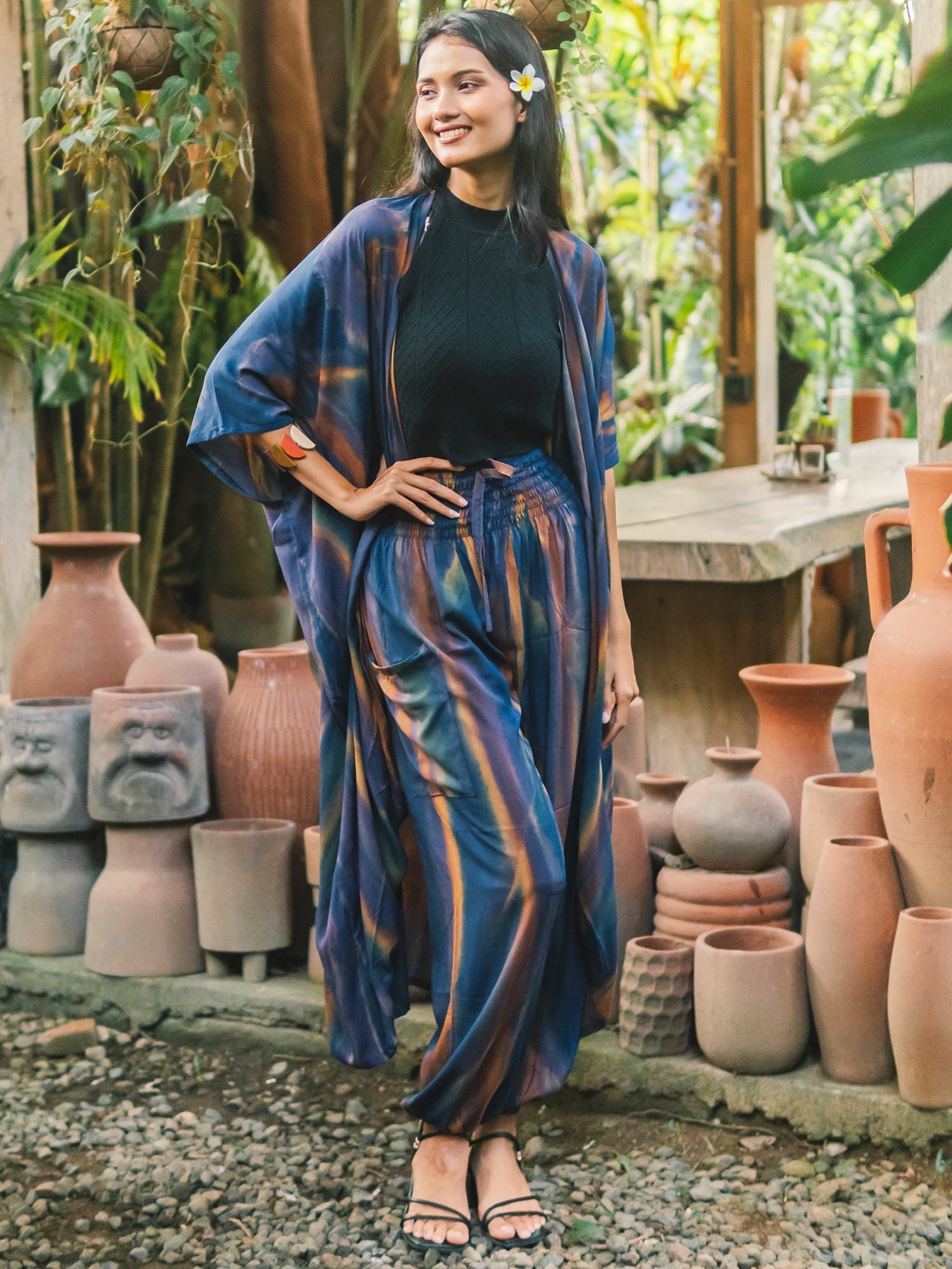 Woman wearing flowing Bali pants and long kimono in serene Bali setting