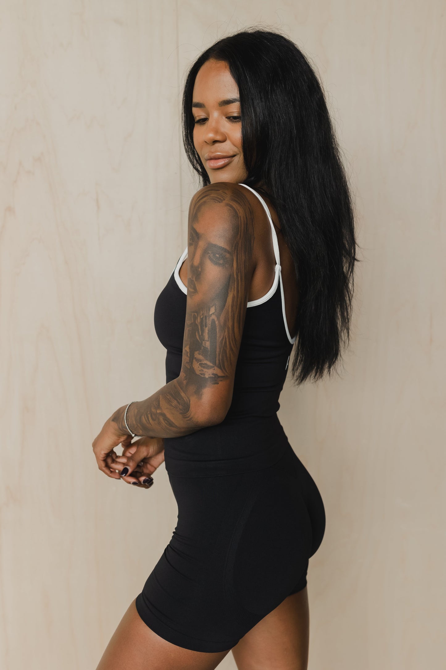 side view of woman wearing a cropped sculpt tank top in black with white trim and matching shorts for yoga and activewear