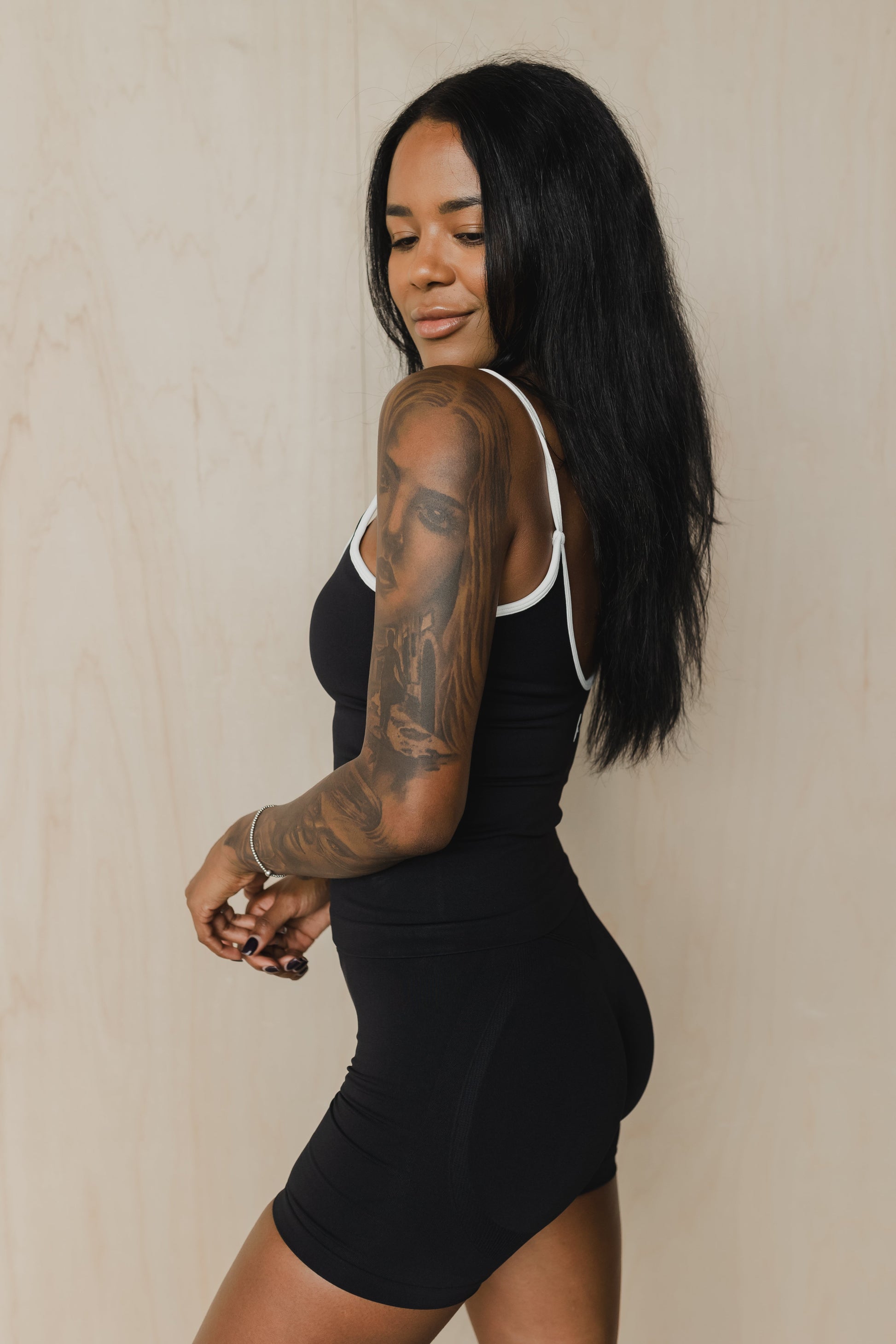 side view of woman wearing a cropped sculpt tank top in black with white trim and matching shorts for yoga and activewear