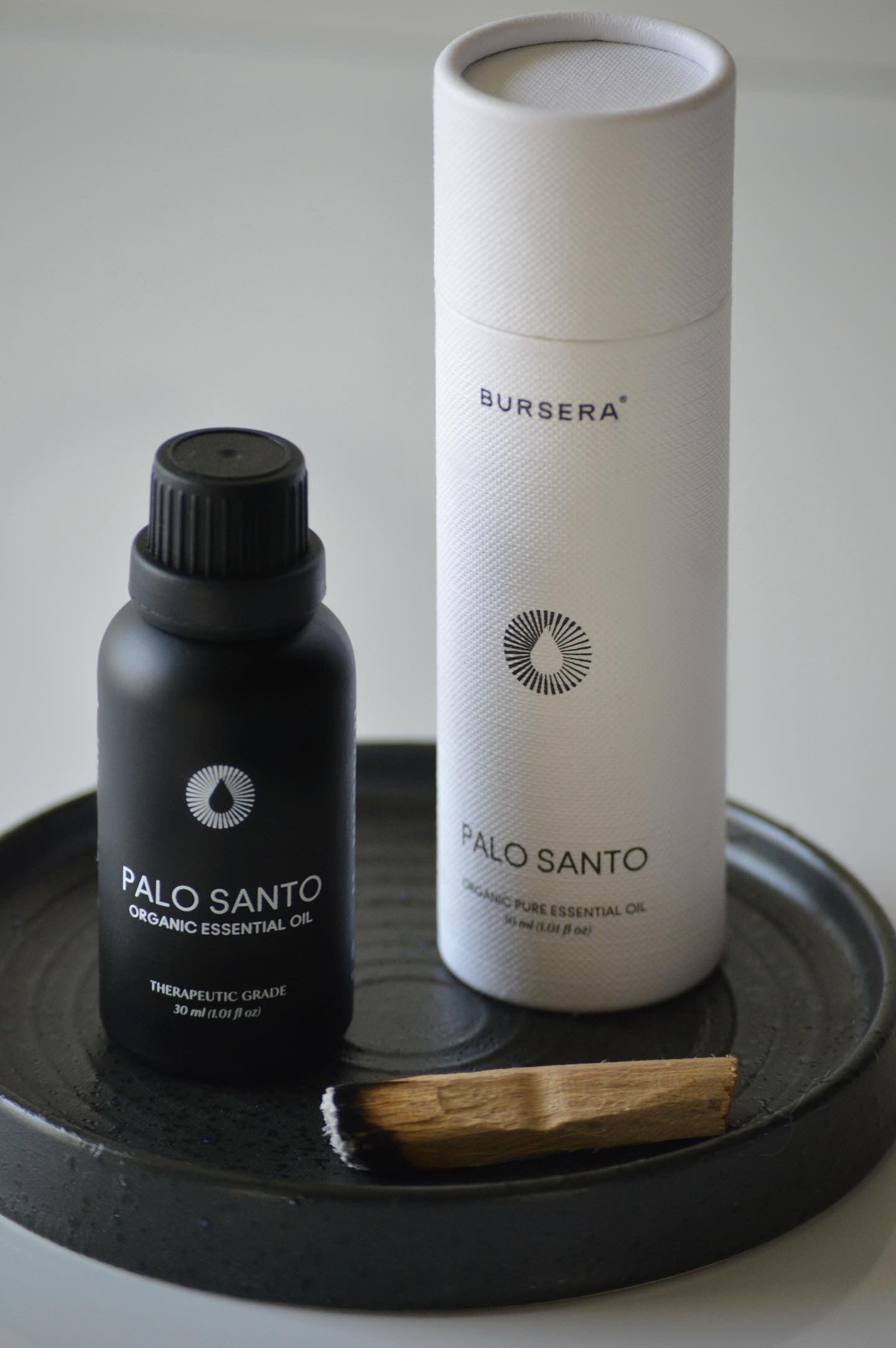 organic palo santo essential oil 30ml aromatherapy on a dark surface.