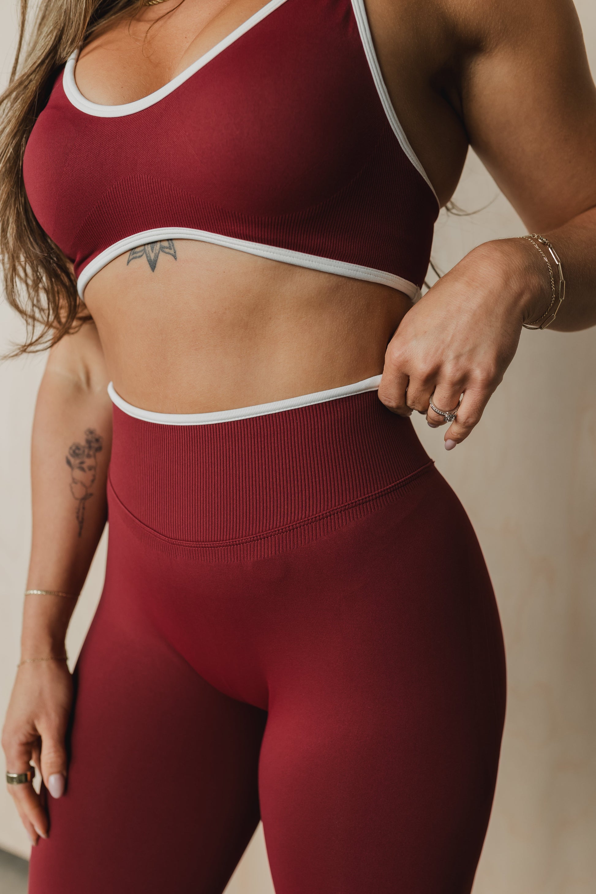 zoomed in front view of a woman wearing booty lift sculpt leggings in maroon for hot yoga and studio workouts