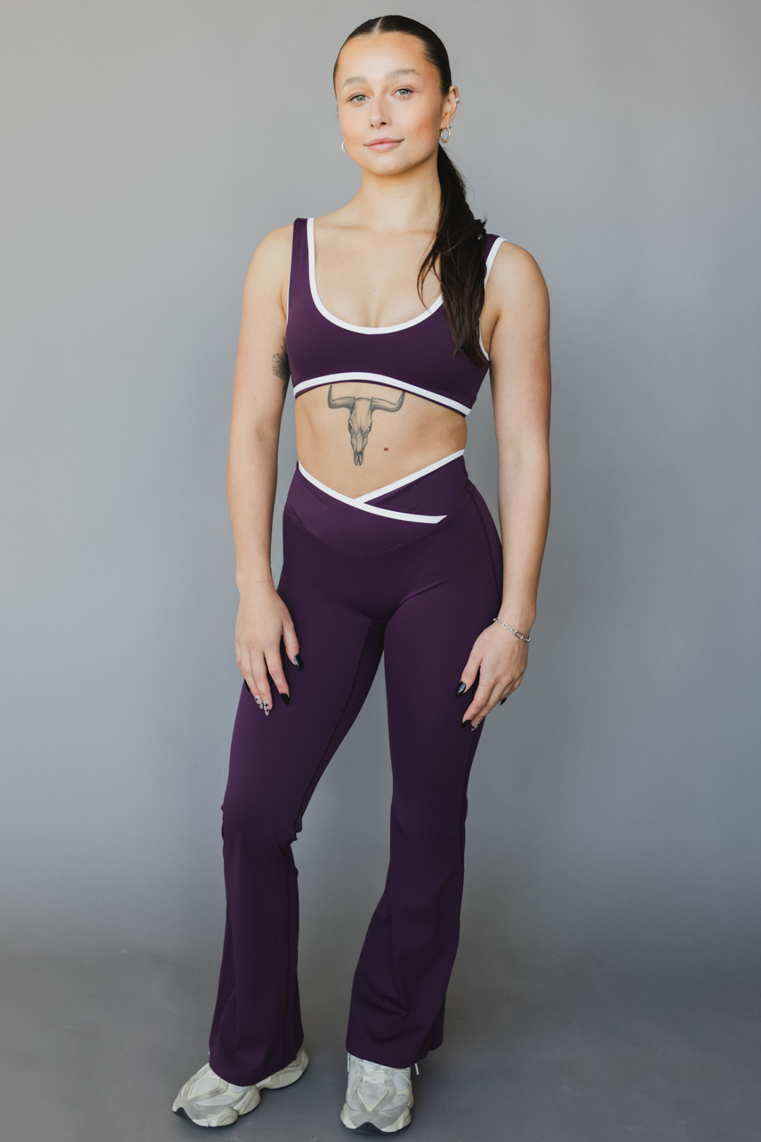 full view of a woman wearing flare leggings in eggplant purple with white trim for workouts and casual athleisure