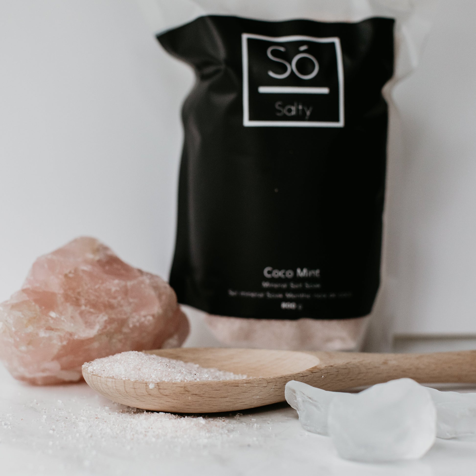 Black bag labeled 'Sö Salty' with a wooden spoon and salt crystals on a light background