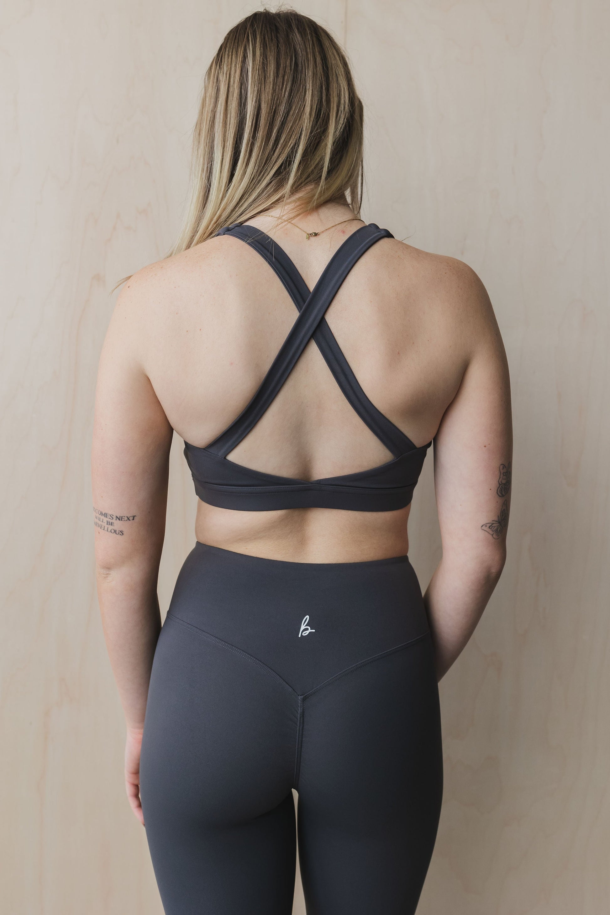 back view of a woman wearing a Fight or Flight high-support sports bra in graphite for yoga and fitness