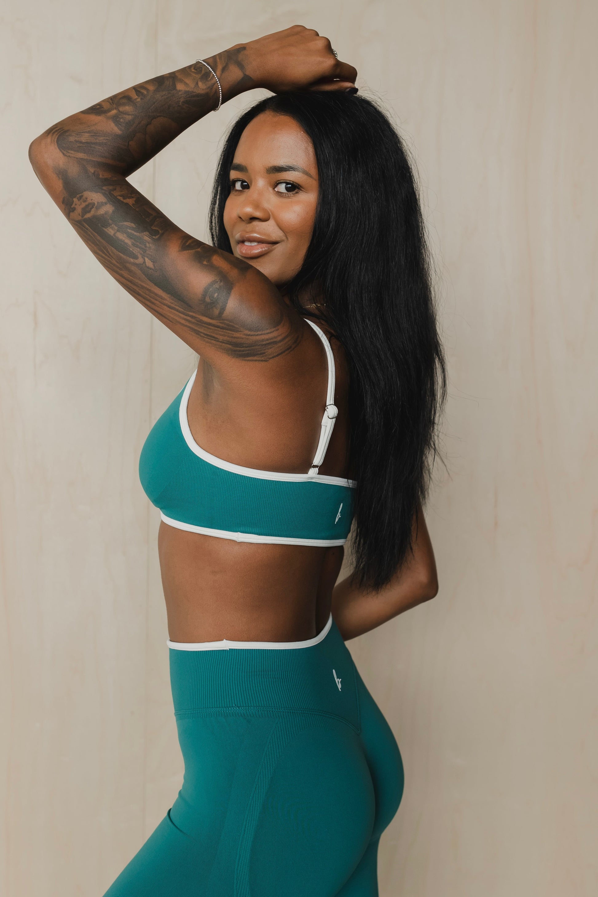 side view of a woman wearing a sculpt sports bra with ribbed piqué fabric in teal for yoga and fitness