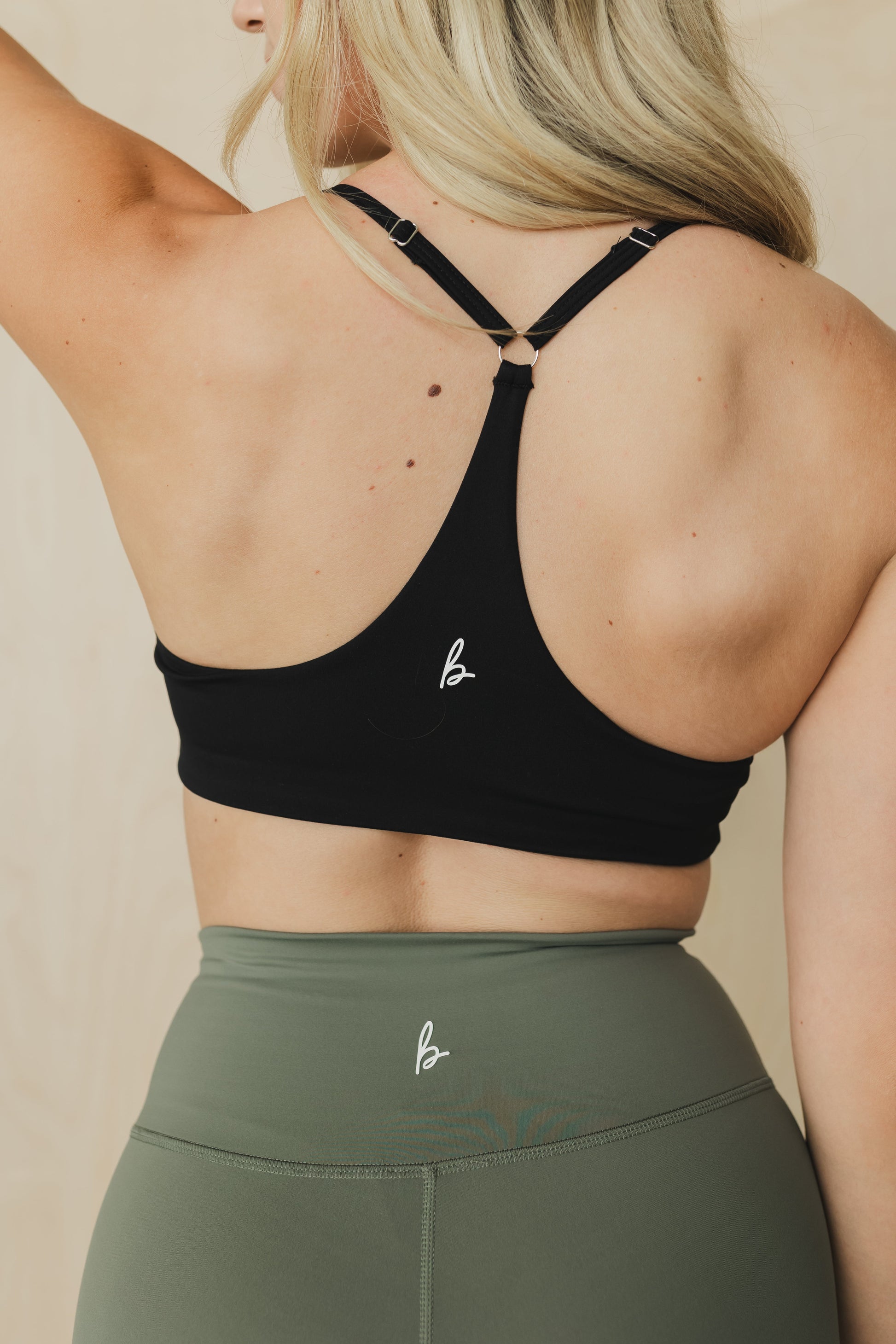 back view of woman wearing divine sports bra in black for high impact training and everyday wear