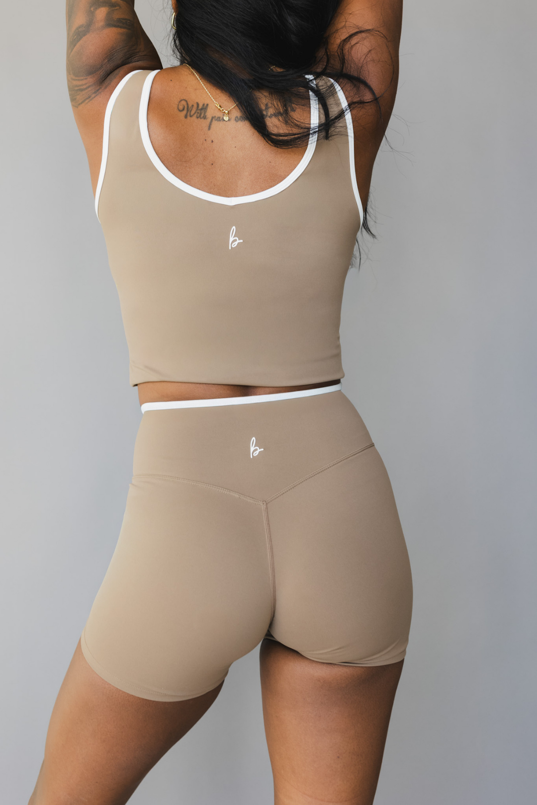 back view of a woman wearing Tina shorts in sable brown with white trim and a matching tank top for athletic wear and loungewear