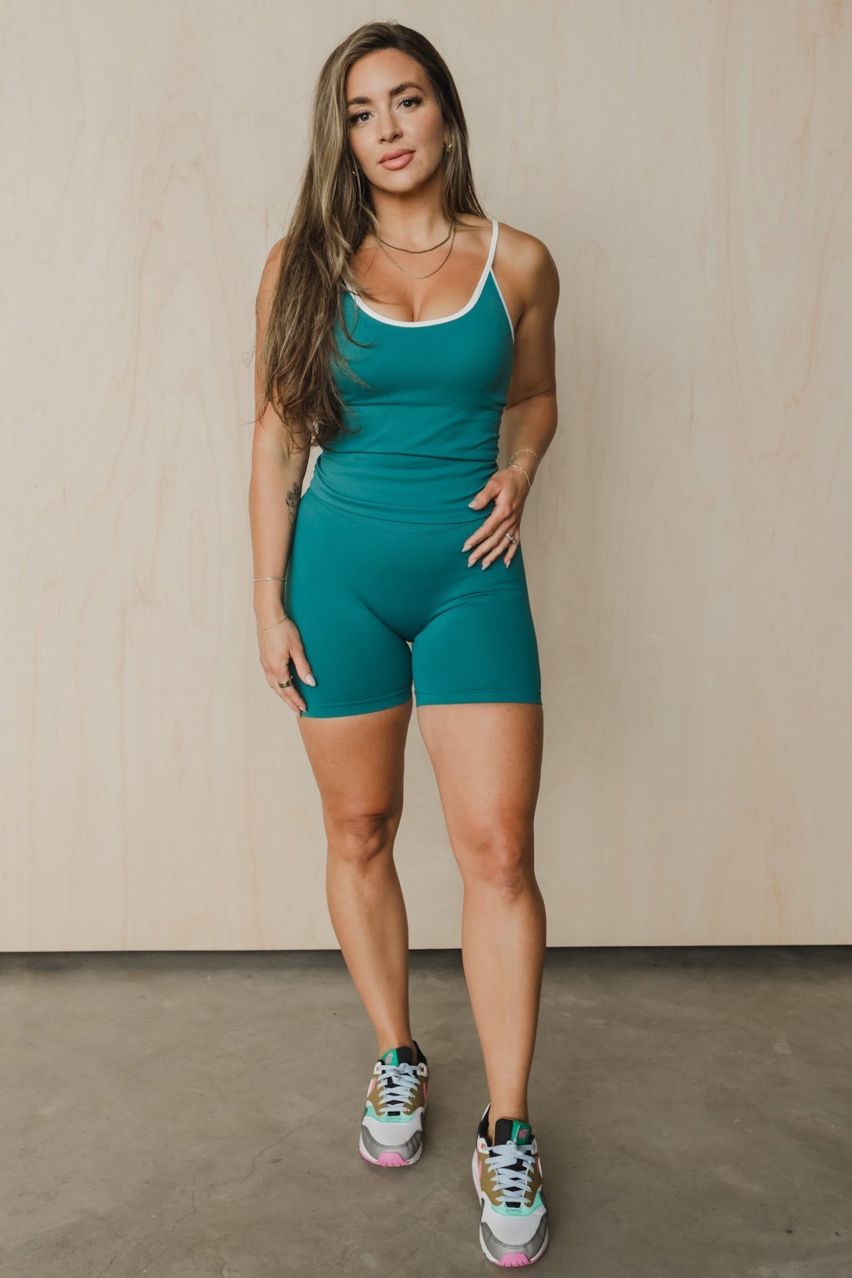 full body front view of a woman wearing booty lift sculpt shorts and matching tank top in teal for hot yoga and summer workouts