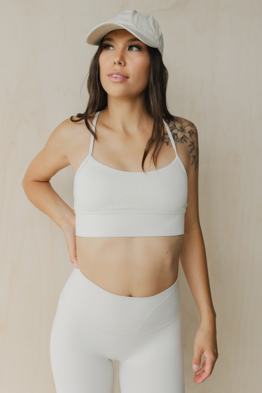 front front view of a woman wearing a barely there sports bra in dove white for yoga and studio workouts