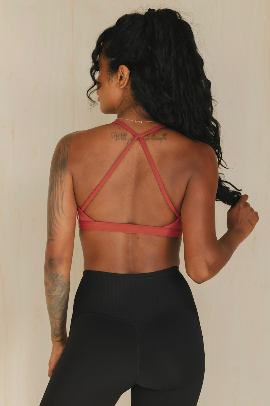 back view of a woman wearing a mini scrunch bra in garnet for yoga and studio workouts