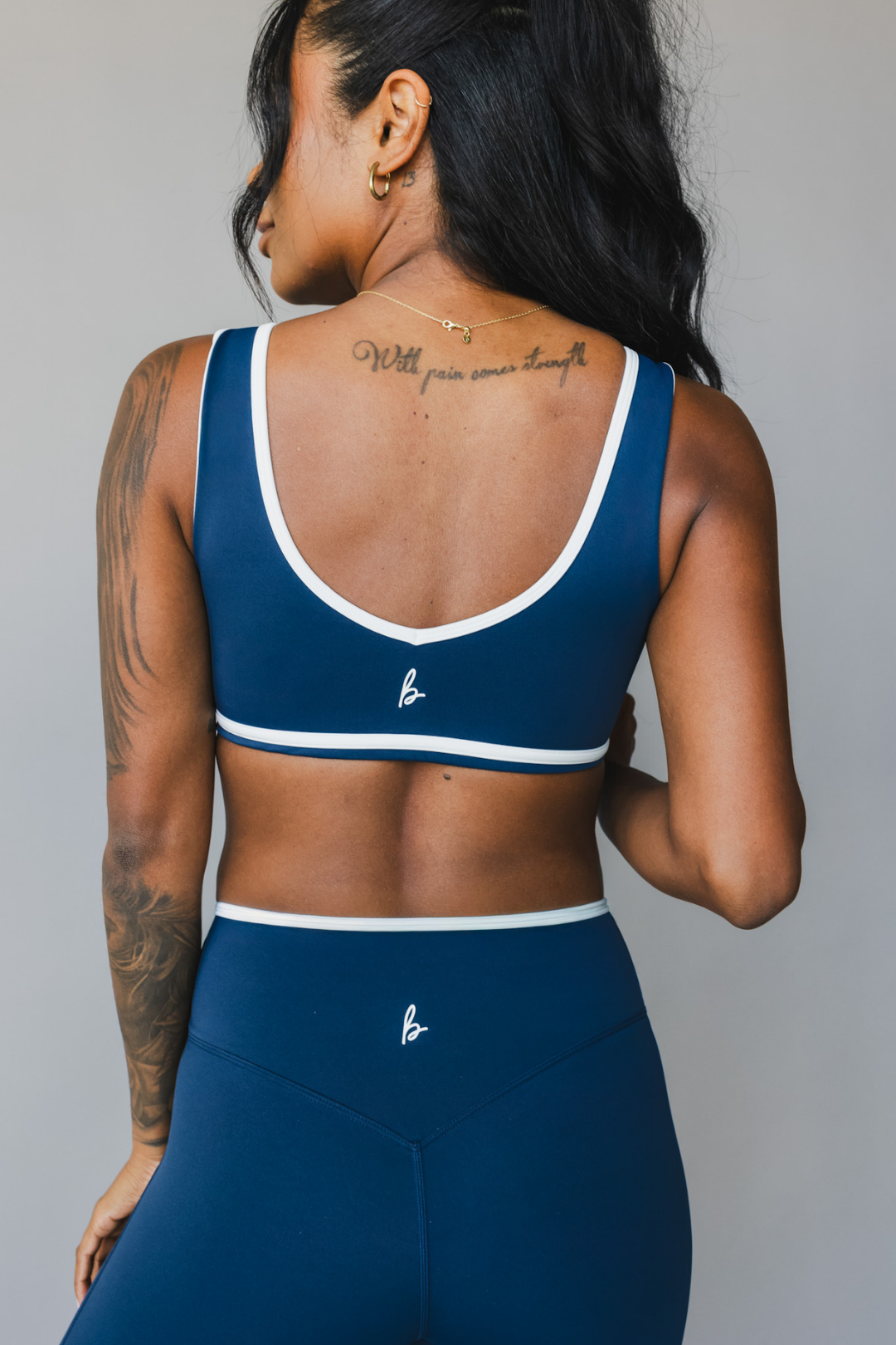 back view of woman wearing a tina sports bra with white trim and scoop neckline in winter blue for yoga and fitness