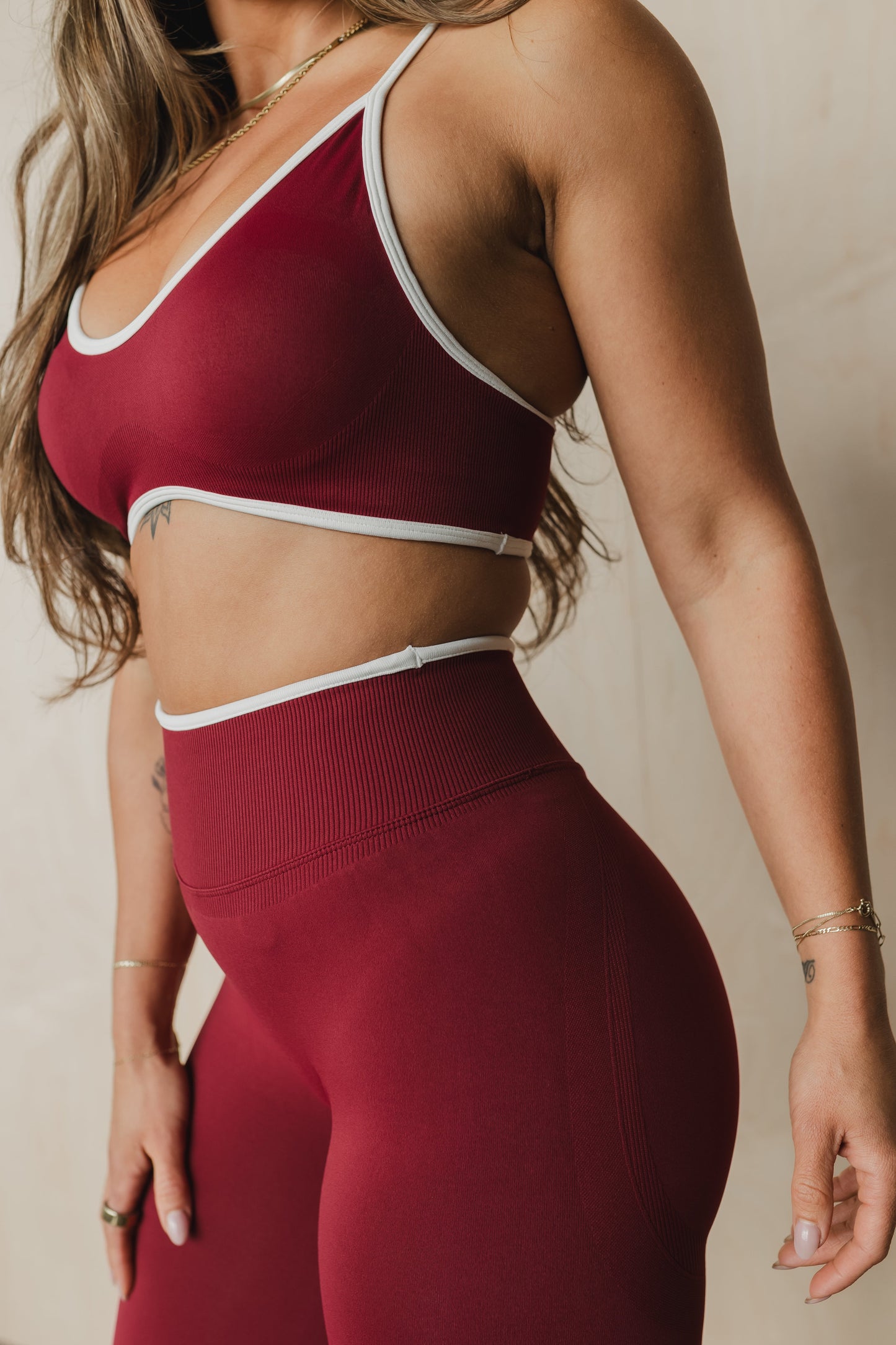 side view of a woman wearing a sculpt sports bra with ribbed piqué fabric in maroon for yoga and fitness