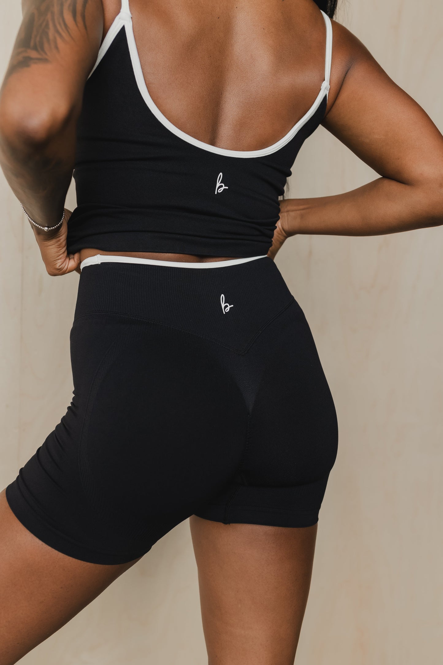 back view of a woman wearing booty lift sculpt shorts and matching tank top in black for hot yoga and summer workouts