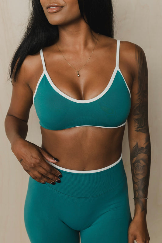 front view of a woman wearing a sculpt sports bra with ribbed piqué fabric in teal for yoga and fitness