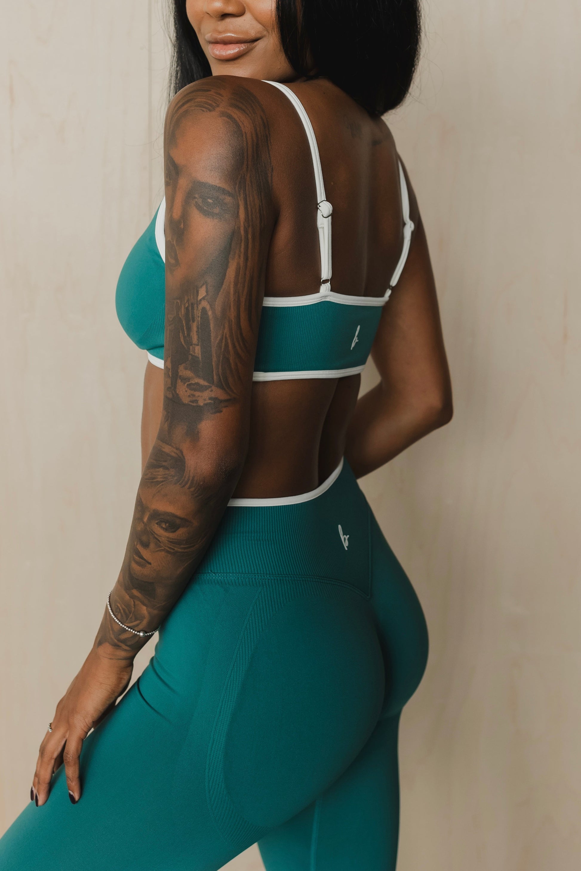 zoomed in side view of a woman wearing booty lift sculpt leggings in teal for the gym and high performance training