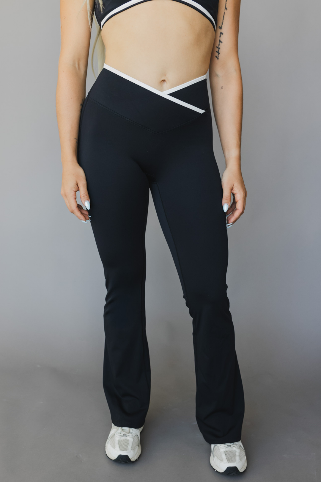 front view of a woman wearing flare leggings in black with white trim for yoga and studio wear
