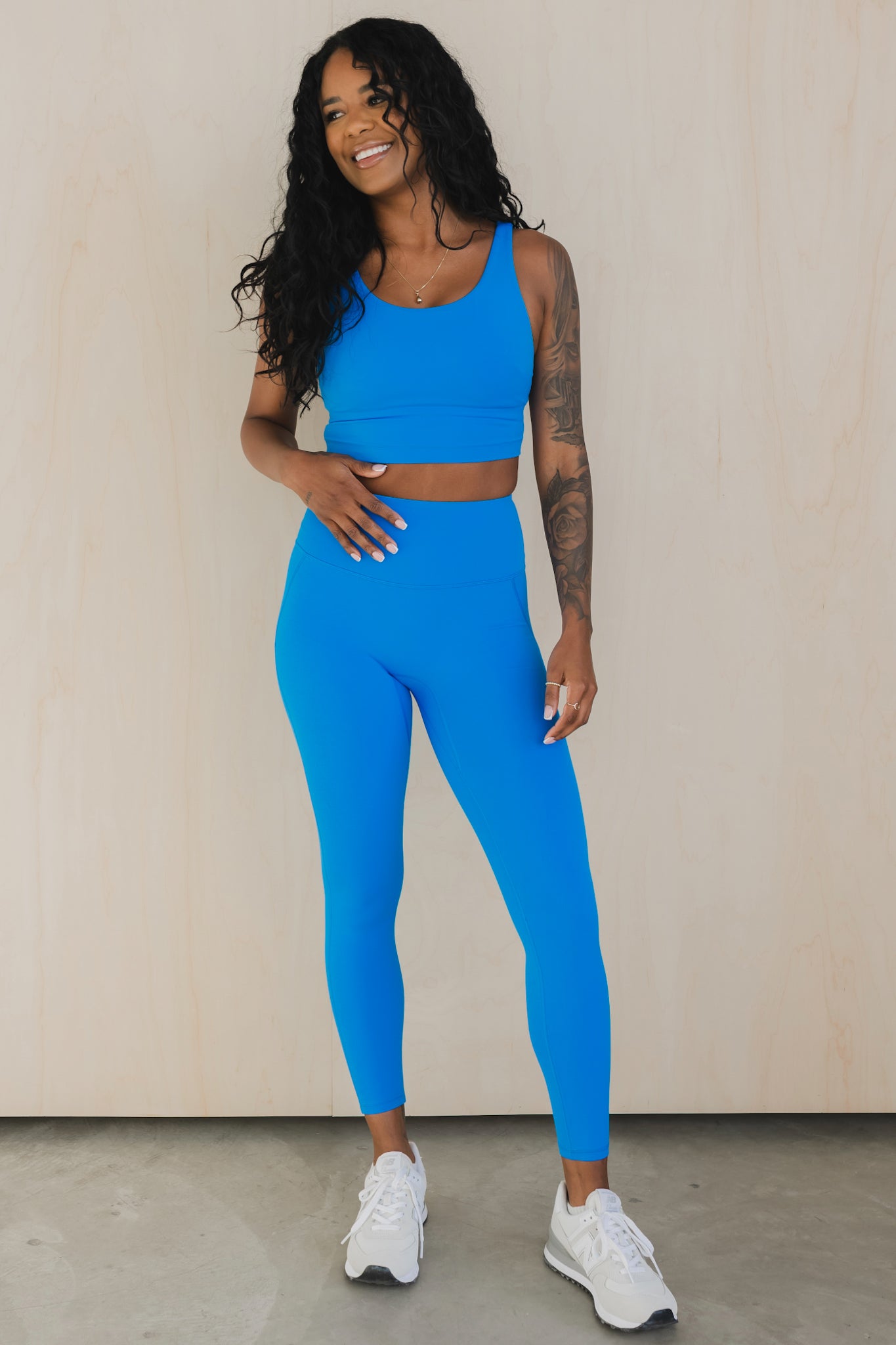 full body view of a woman wearing wrap back sports bra and matching leggings in true blue for yoga and fitness