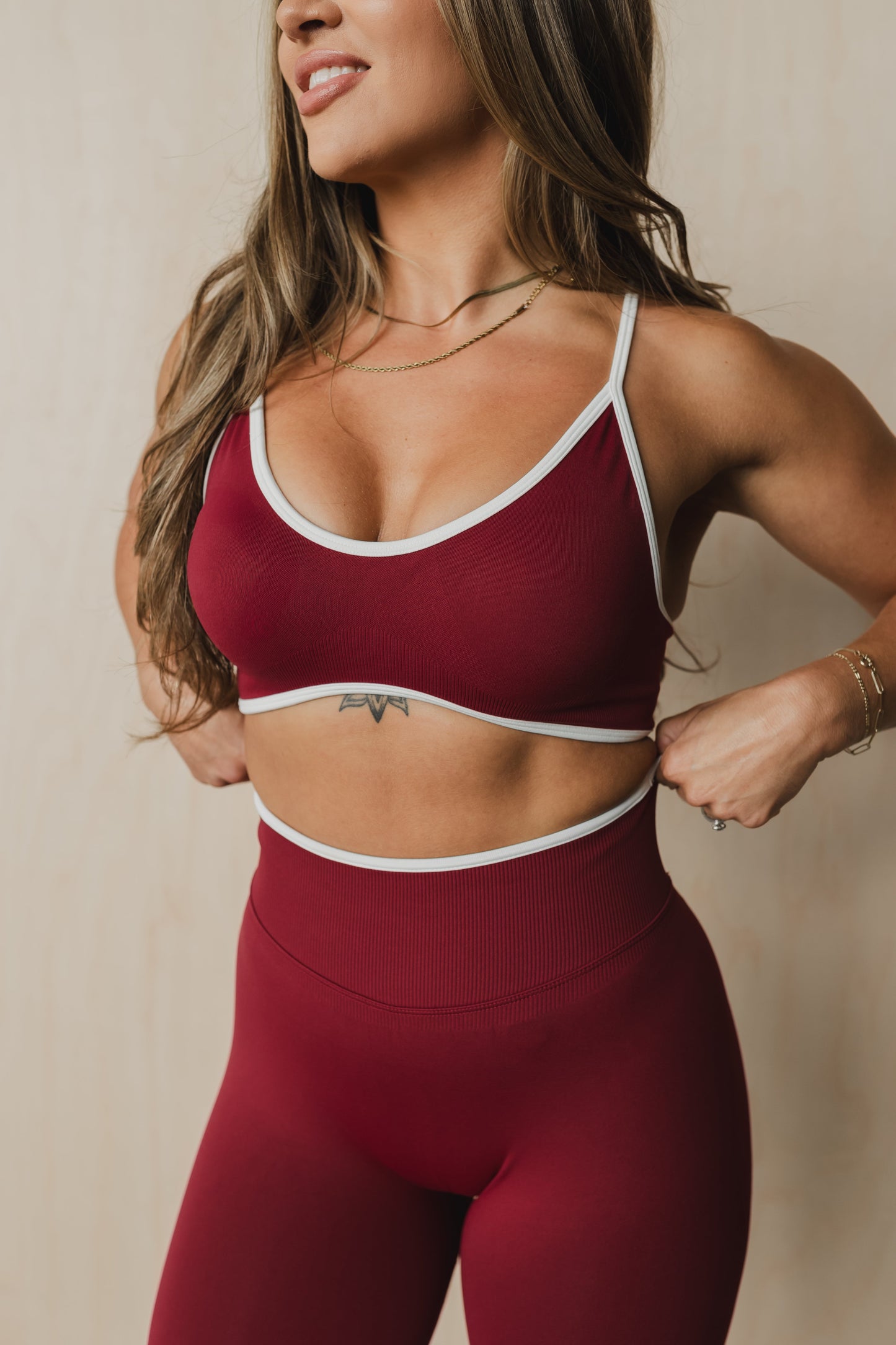 front view of a woman wearing a sculpt sports bra with ribbed piqué fabric in maroon for yoga and fitness