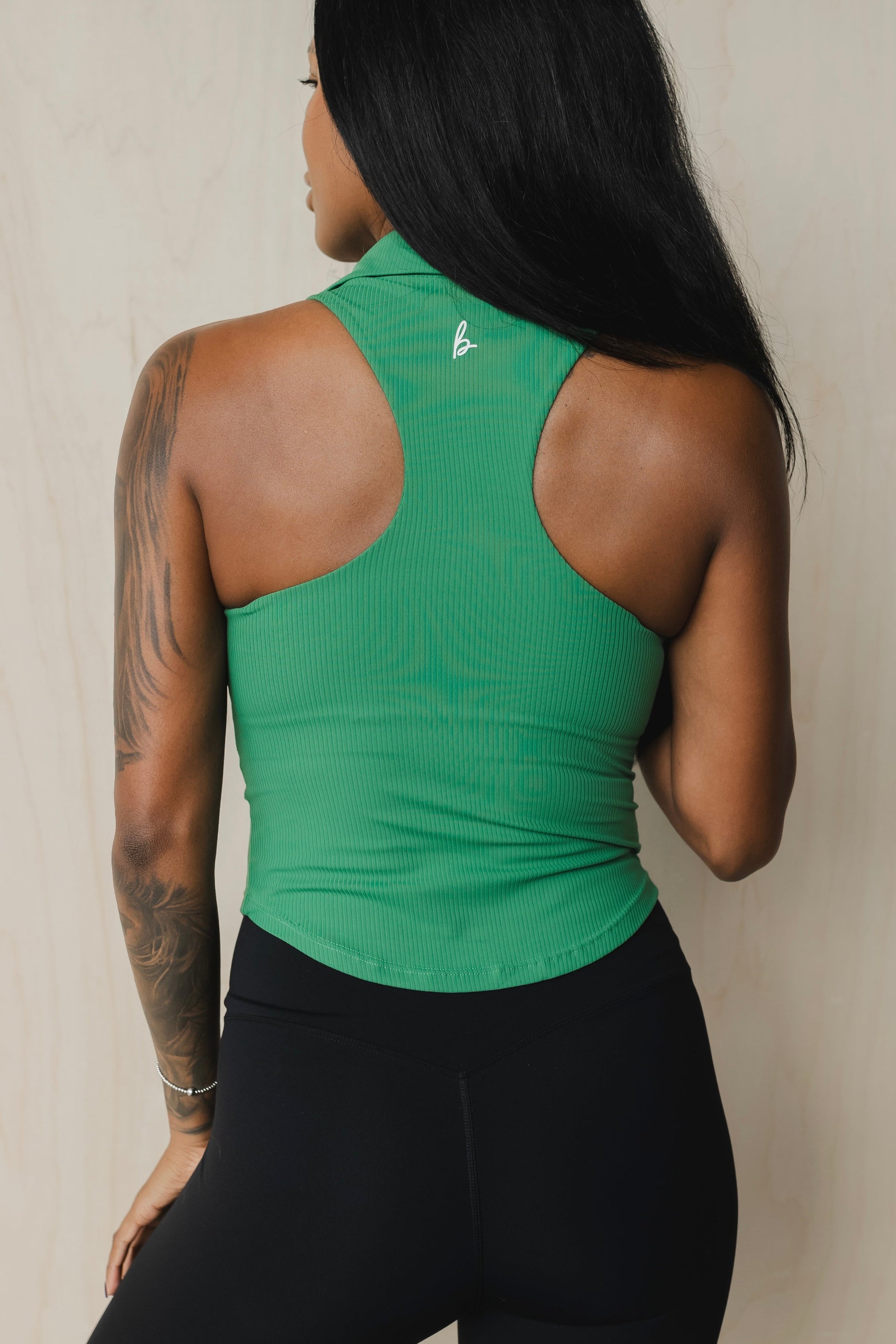 back view of a woman wearing a Ace tank top in shamrock green for golf yoga and activewear