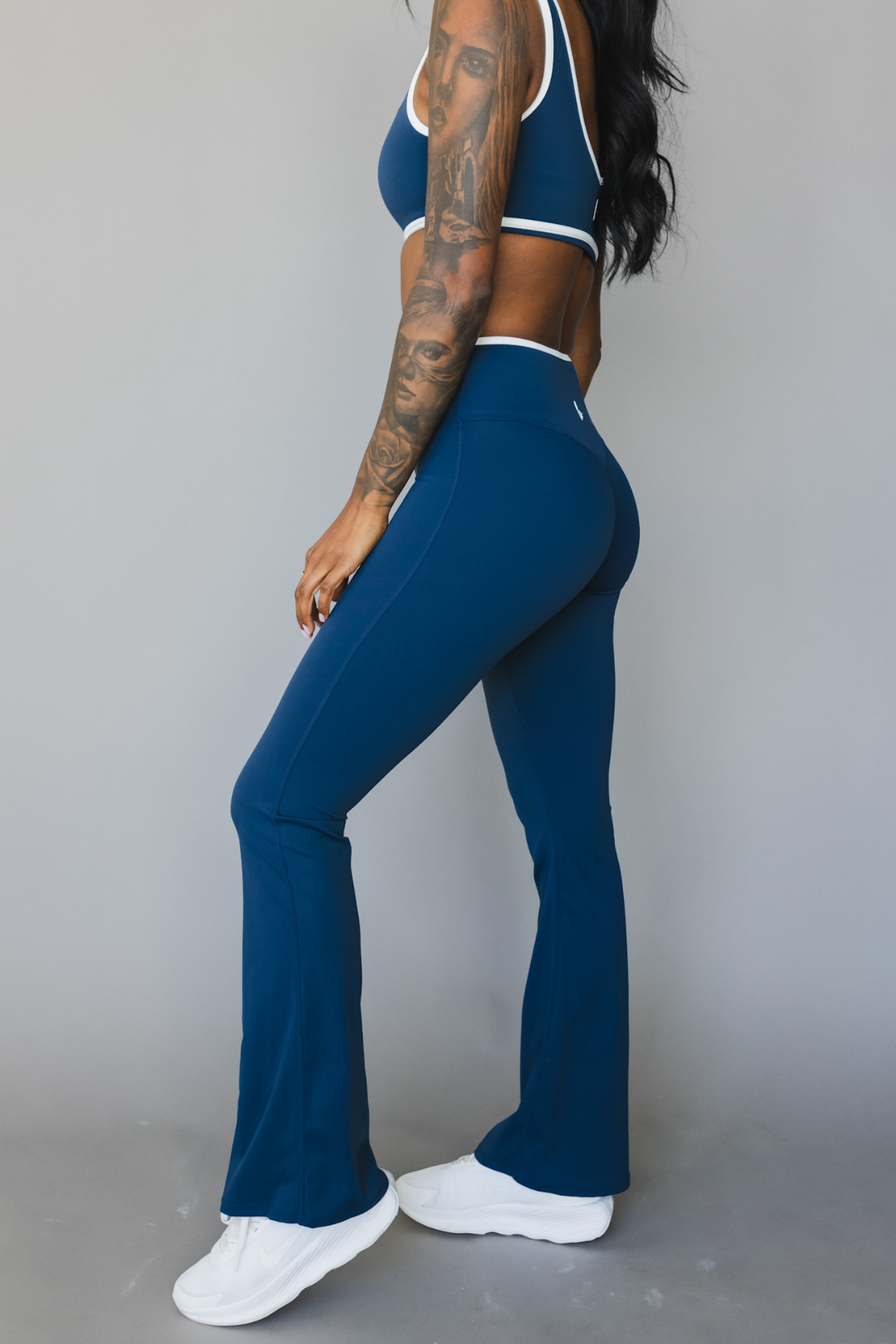 side view of a woman wearing flare leggings in winter blue with white trim for the gym and versatile everyday wear