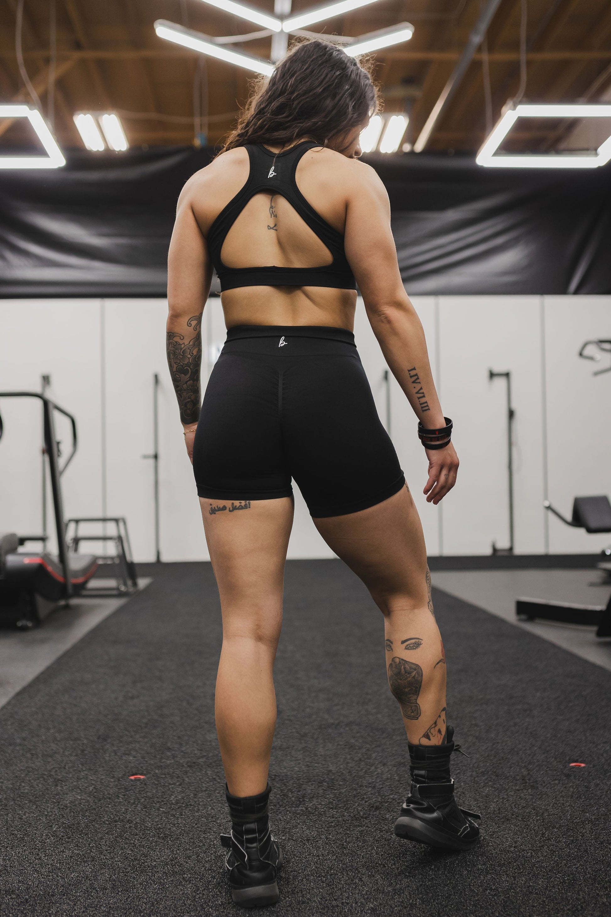 back view of a woman wearing mini scrunch shorts in black for yoga and summer activewear
