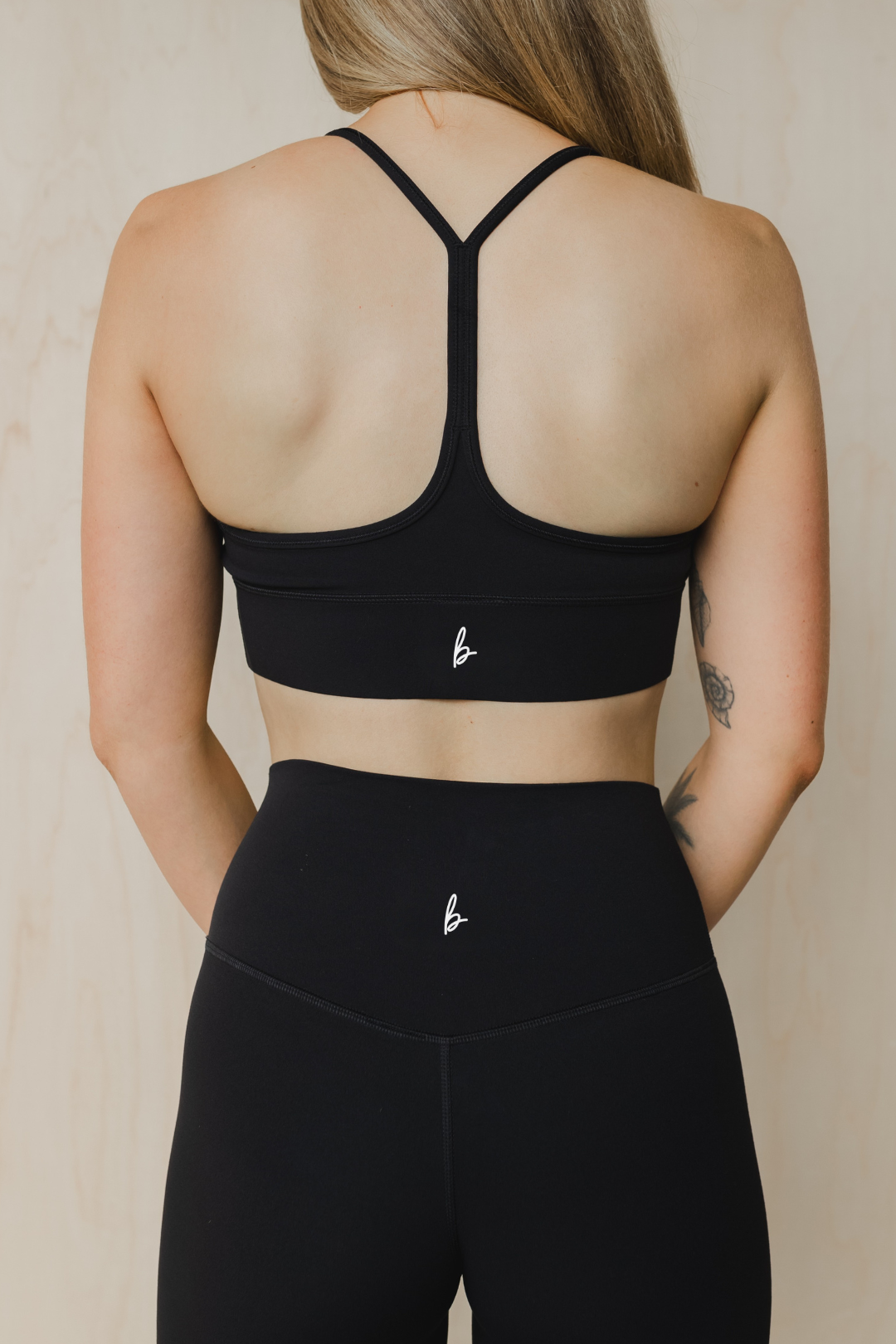 back view of a woman wearing a barely there sports bra in black for high impact training and everyday wear