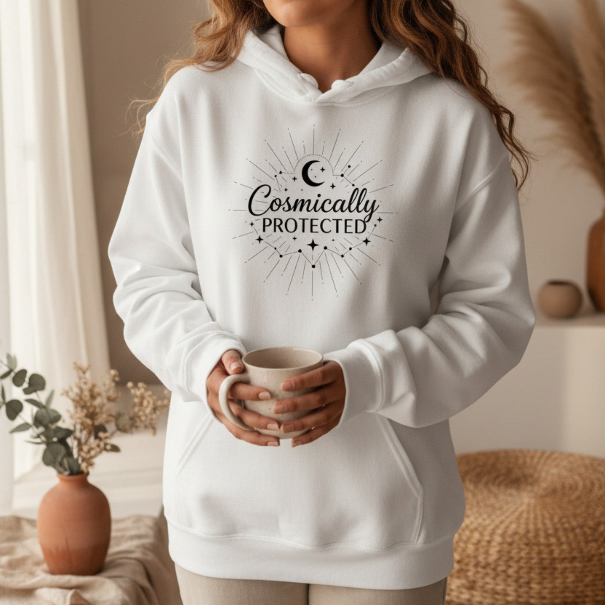 White cosmically protected hoodie with black celestial sunburst print — clean ethereal spiritual gift for the woman who carries quiet faith and cosmic energy into every room