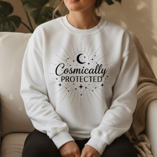 White cosmically protected crewneck sweatshirt with black celestial sunburst and crescent moon graphic — spiritual protection gift for women who trust the universe