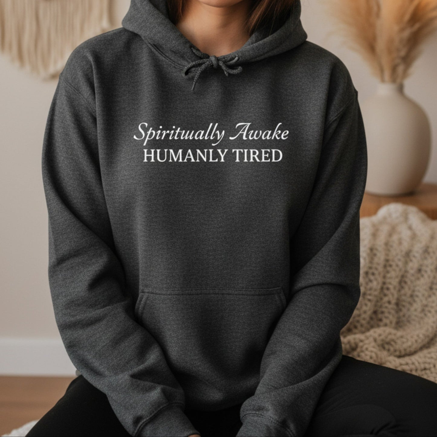 Dark heather gray Spiritually Awake Humanly Tired pullover hoodie with white script and serif print — cozy funny spiritual gift for the woman who meditates every morning and still needs three coffees