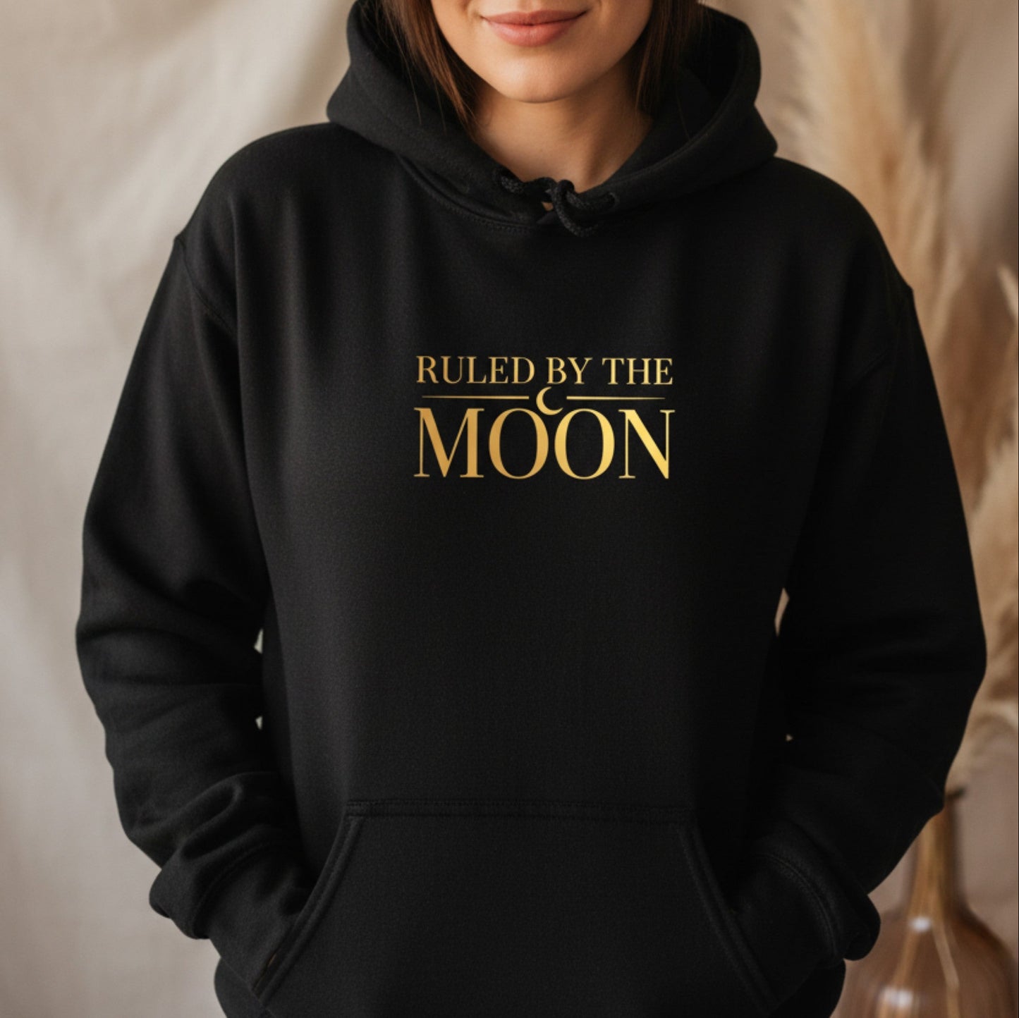 Black ruled by the moon hoodie with gold lunar typography — cozy witchy pullover for astrology lovers who wear their night sky energy everywhere they go