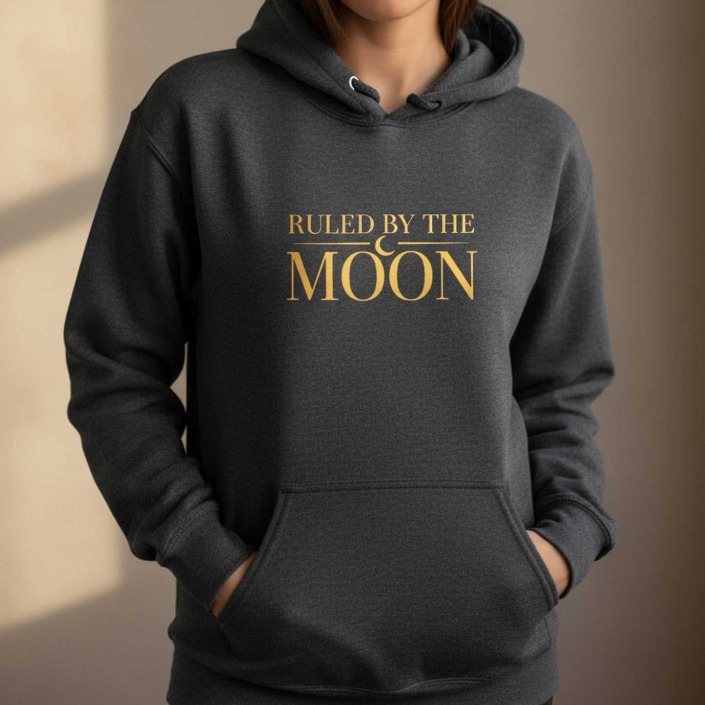 Dark heather gray pullover hoodie with gold crescent moon graphic — celestial gift for the woman who sets intentions by moonlight and never stops believing in her own magic