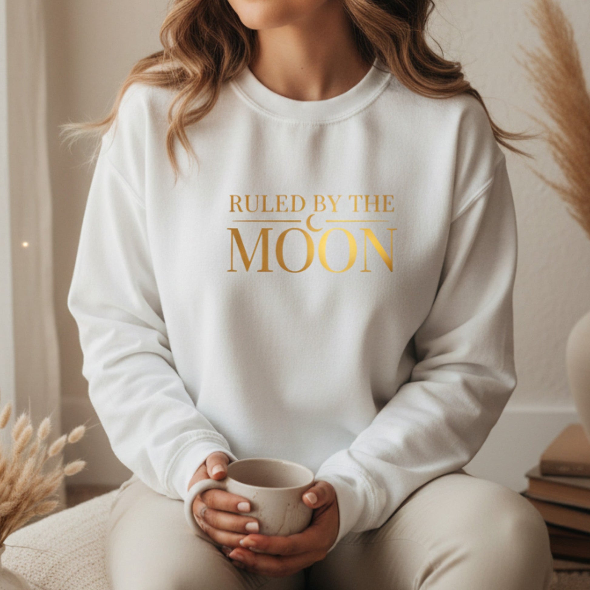 White fleece crewneck with gold ruled by the moon graphic — boho spiritual sweatshirt for new moon rituals and cozy self-care days