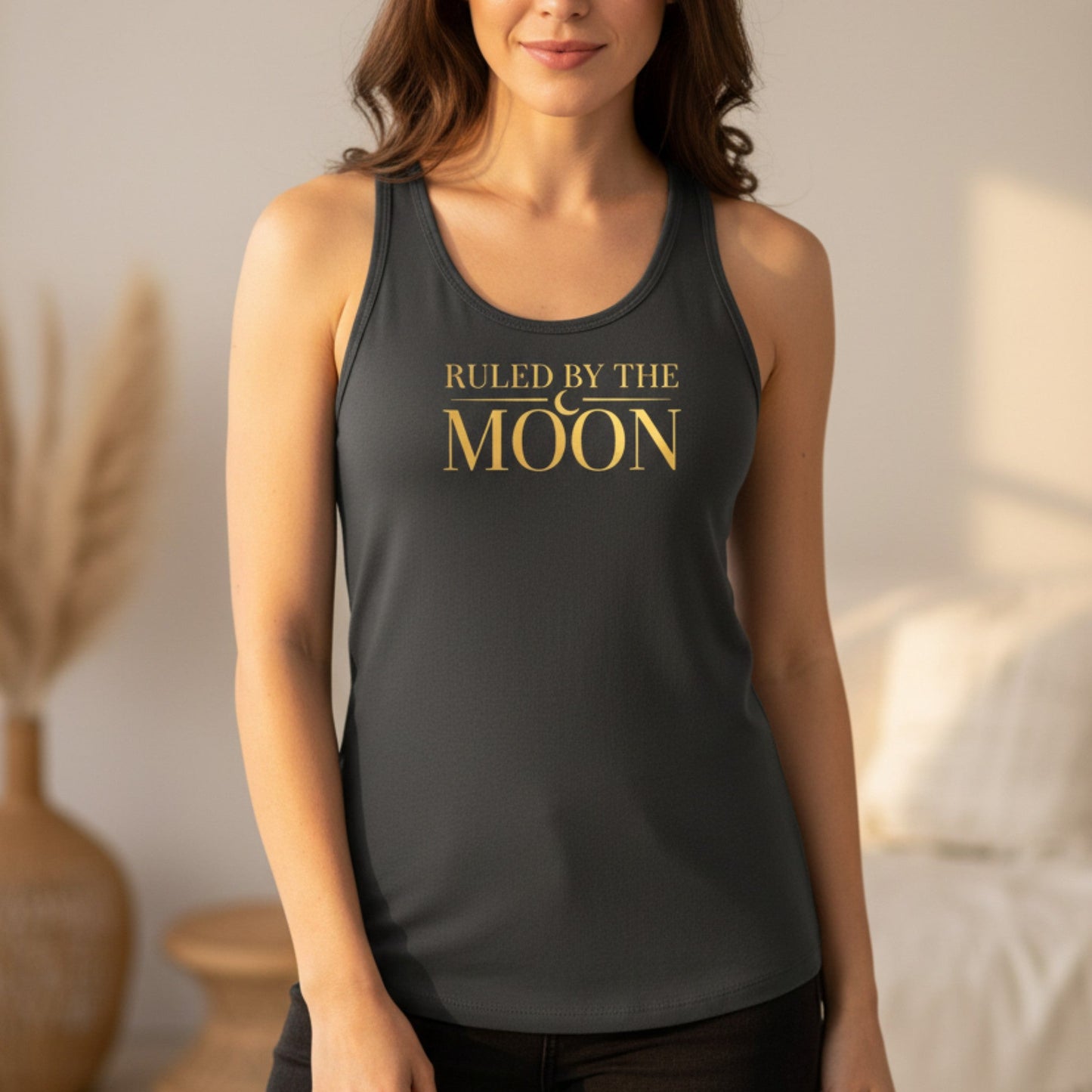 Gray Ruled By The Moon racerback tank top with gold celestial typography and crescent moon graphic — lightweight moon lover gift for women