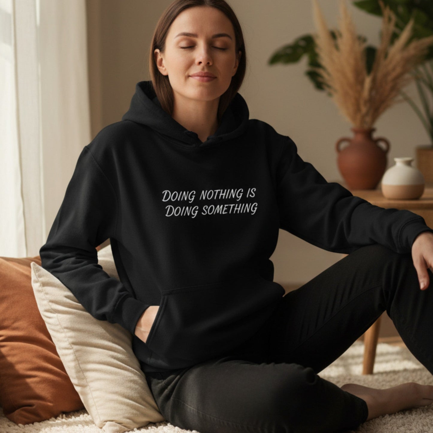 Woman wearing a self-care hoodie with the phrase "Doing Nothing Is Doing Something" — cozy pullover gift for women who prioritize rest
