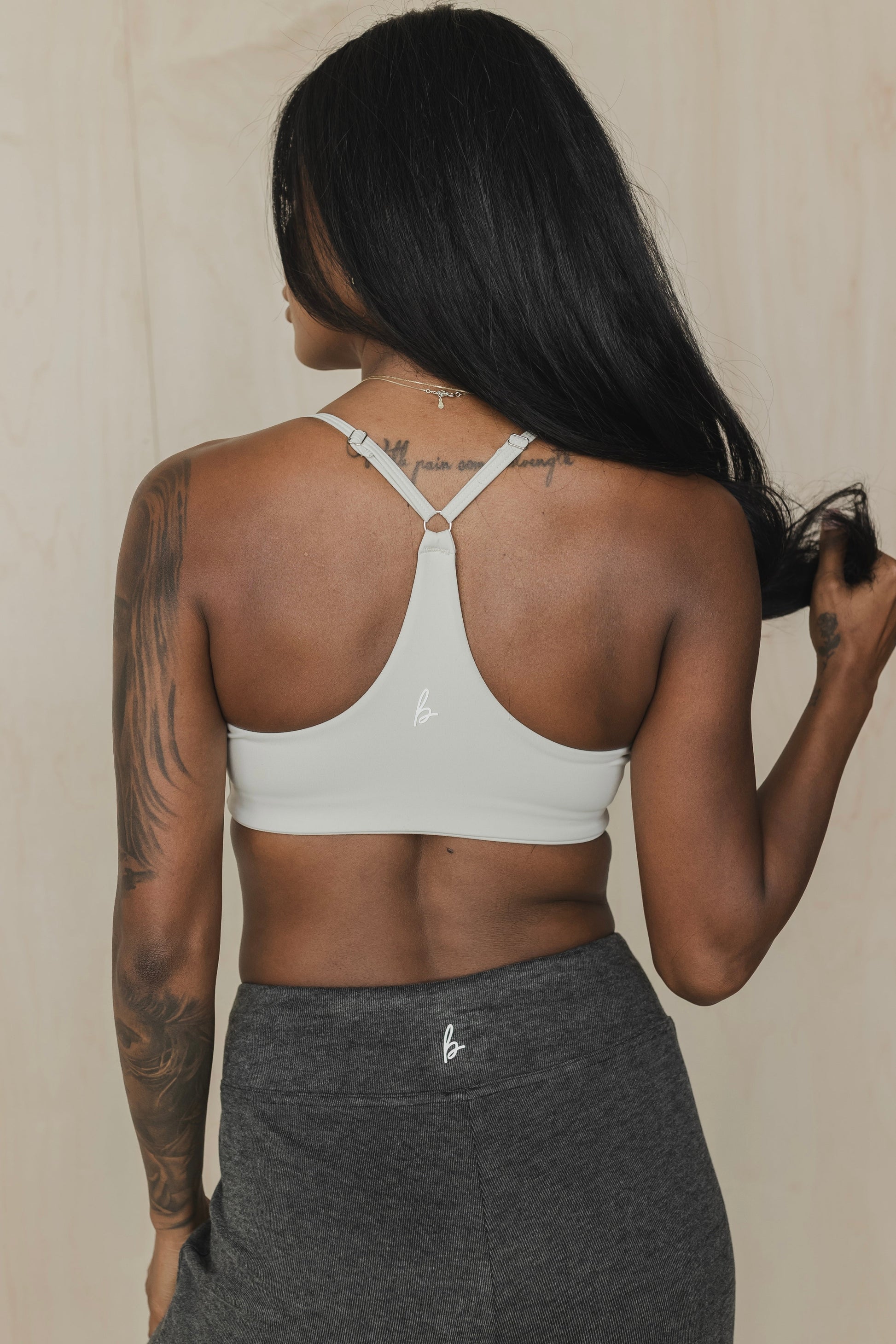 back view of woman wearing divine sports bra in greyish white for hot yoga and summer workouts