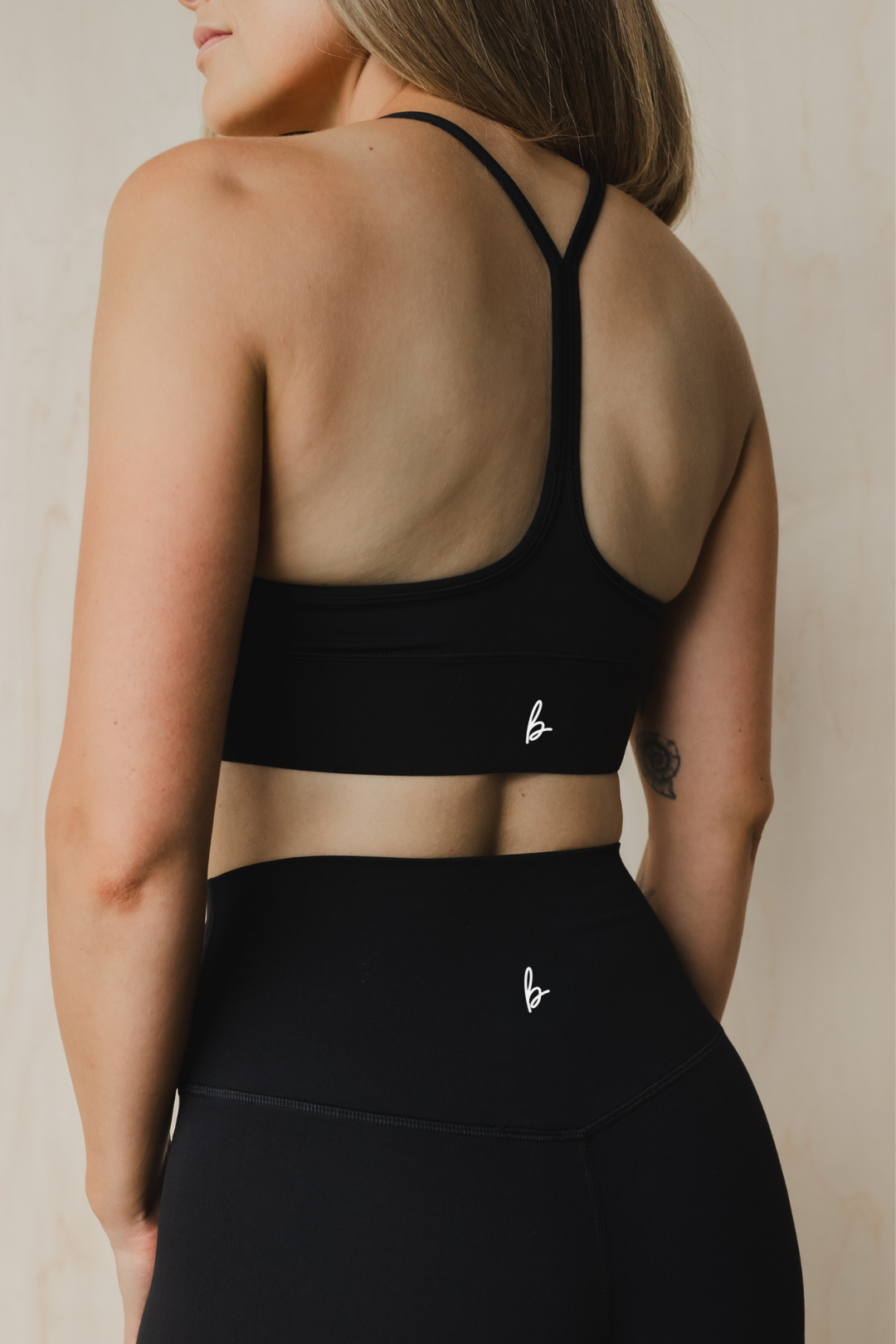 close up back view of a woman wearing a barely there sports bra in black for high impact training and everyday wear