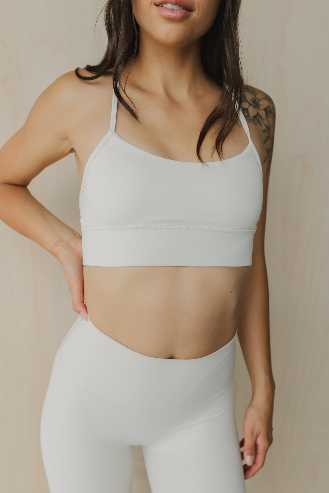 close up front view of a woman wearing a barely there sports bra in dove white for yoga and studio workouts