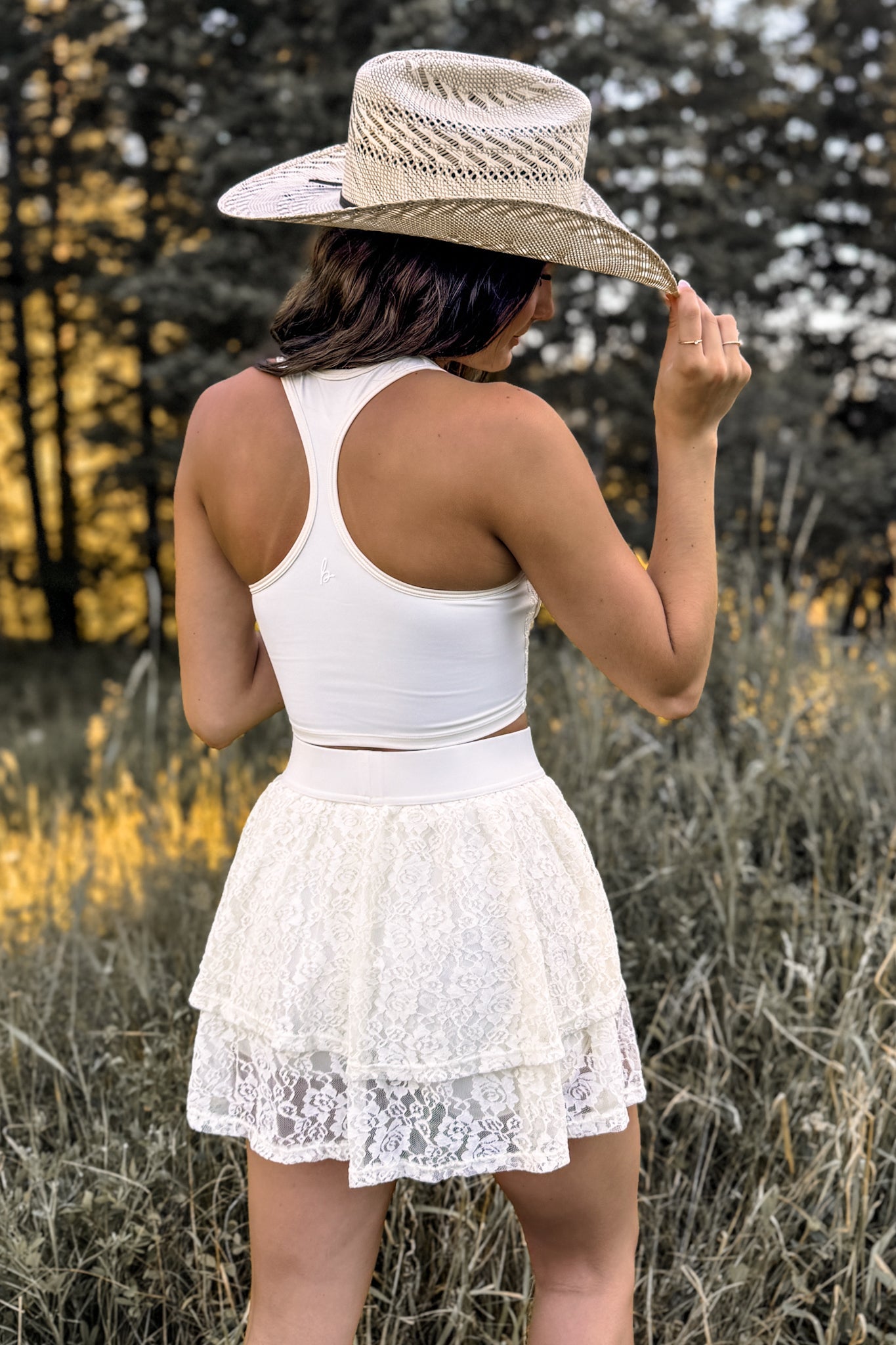 back view of a woman wearing a stampede corset-inspired crop top in cream ivory bfor festivals and activewear