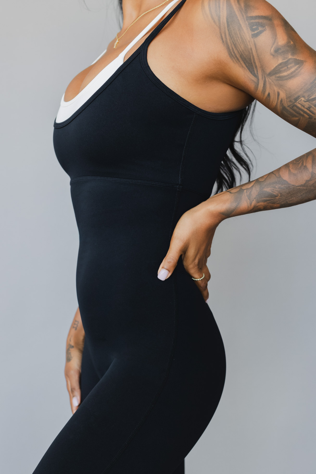 side view of a woman wearing tina bodysuit in black for yoga and studio wear