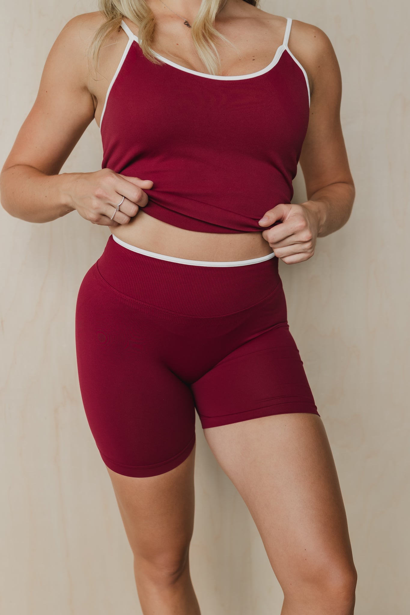 close up front view of a woman wearing booty lift sculpt shorts and matching tank top in maroon for hot yoga and summer workouts