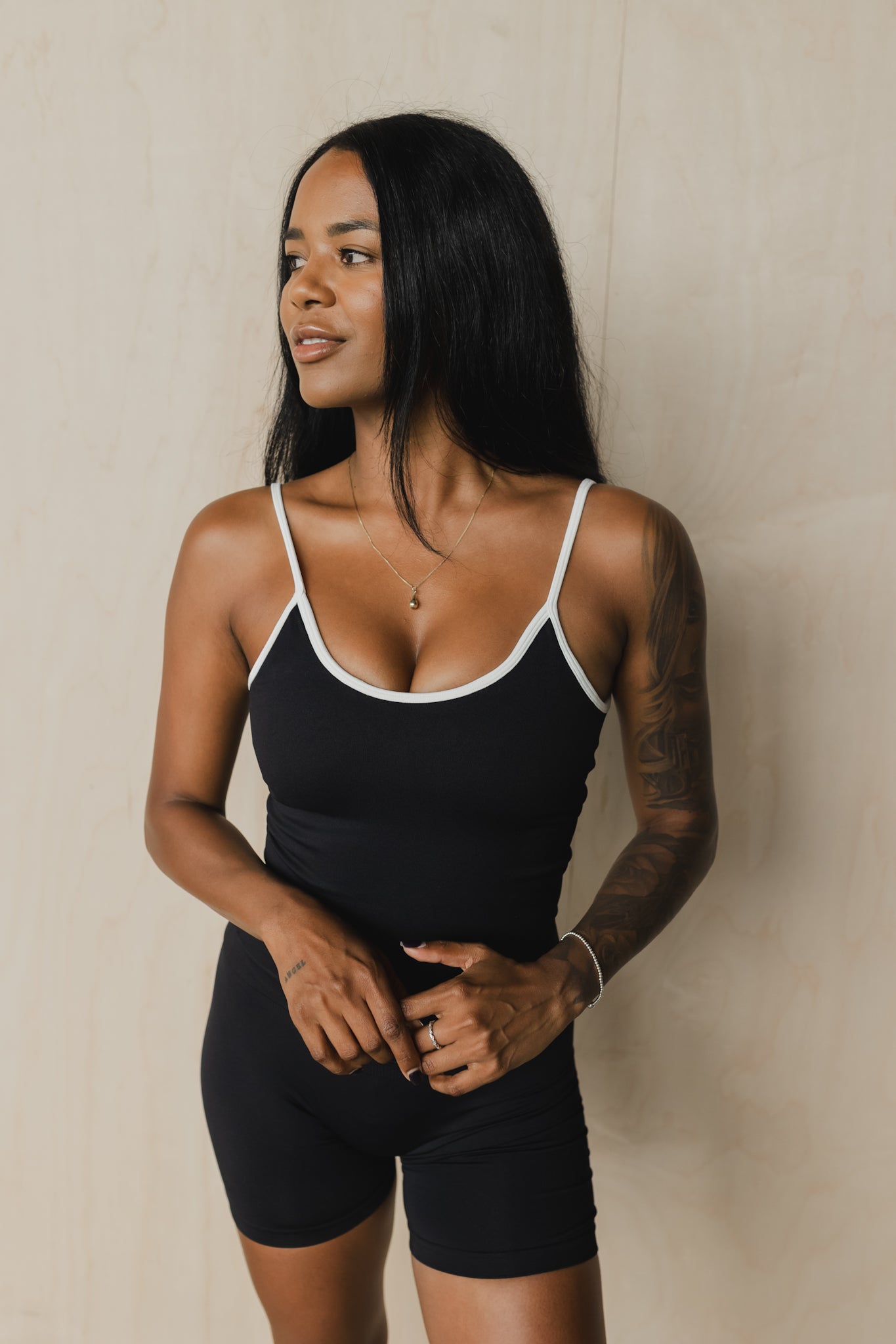 full body front view of woman wearing a cropped sculpt tank top in black with white trim and matching shorts for yoga and activewear